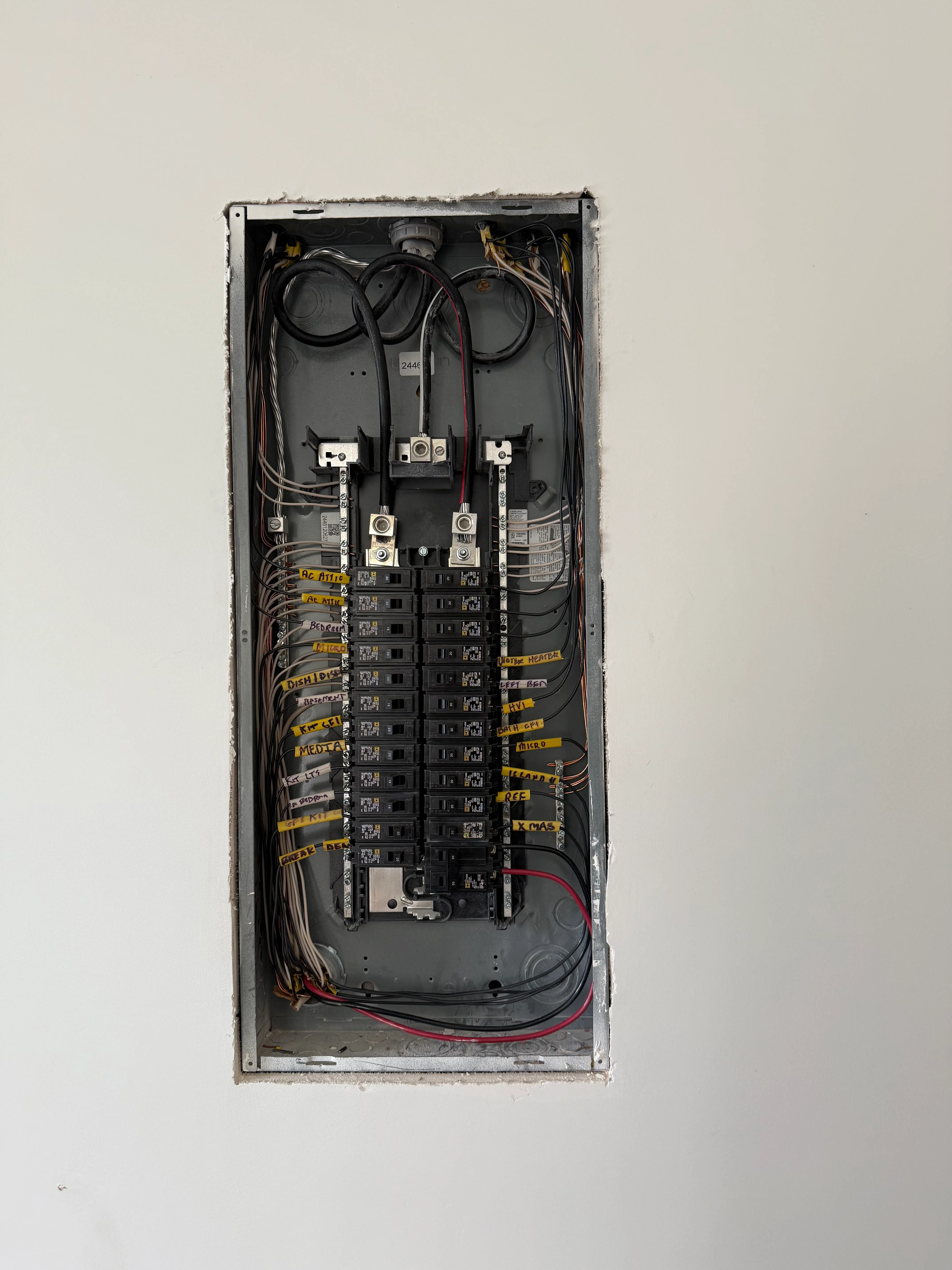 Installed electrical panel with breakers and organized yellow-labeled wiring