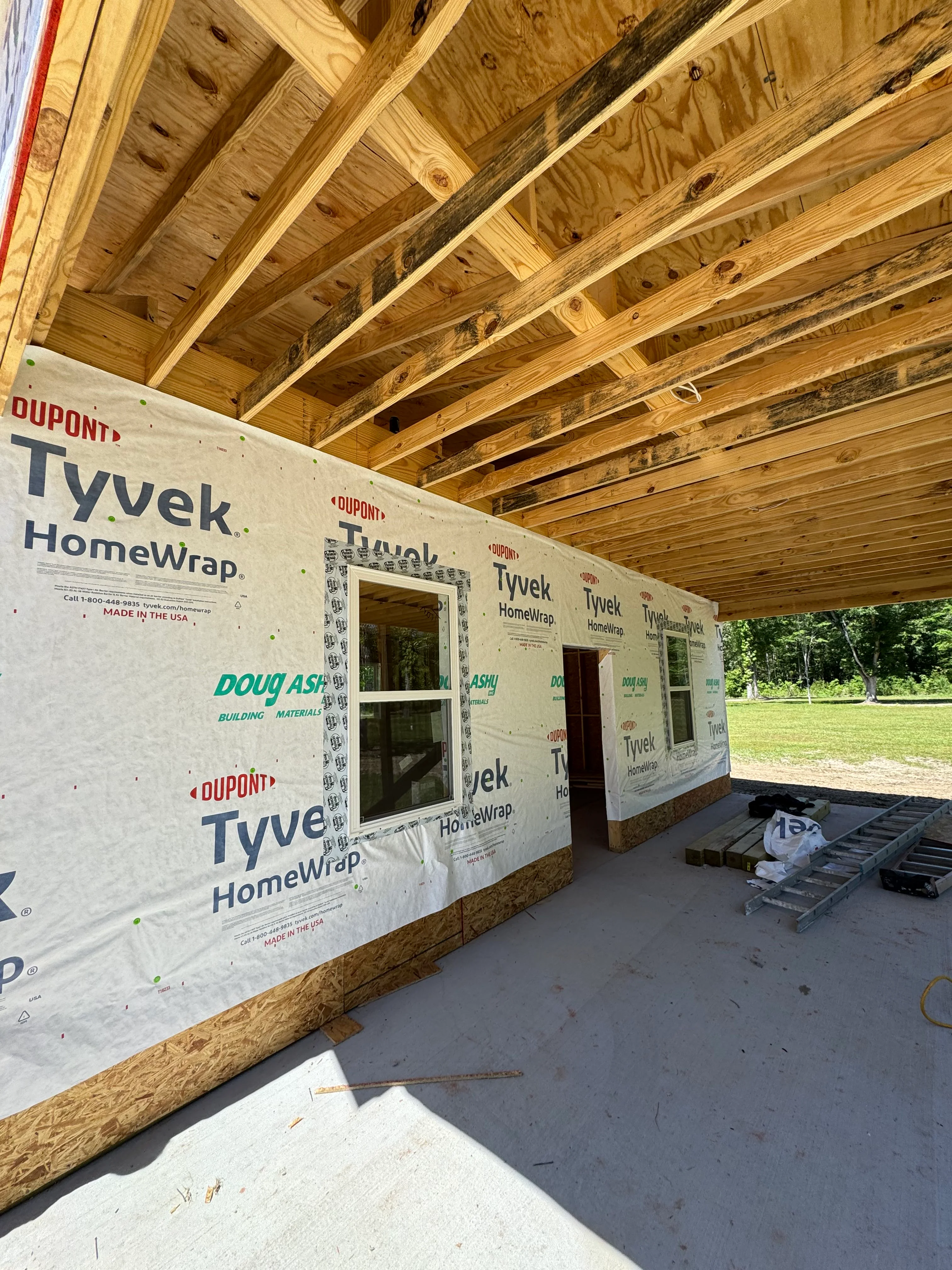 Interior framing with wooden joists, Tyvek wrap, and installed windows during construction