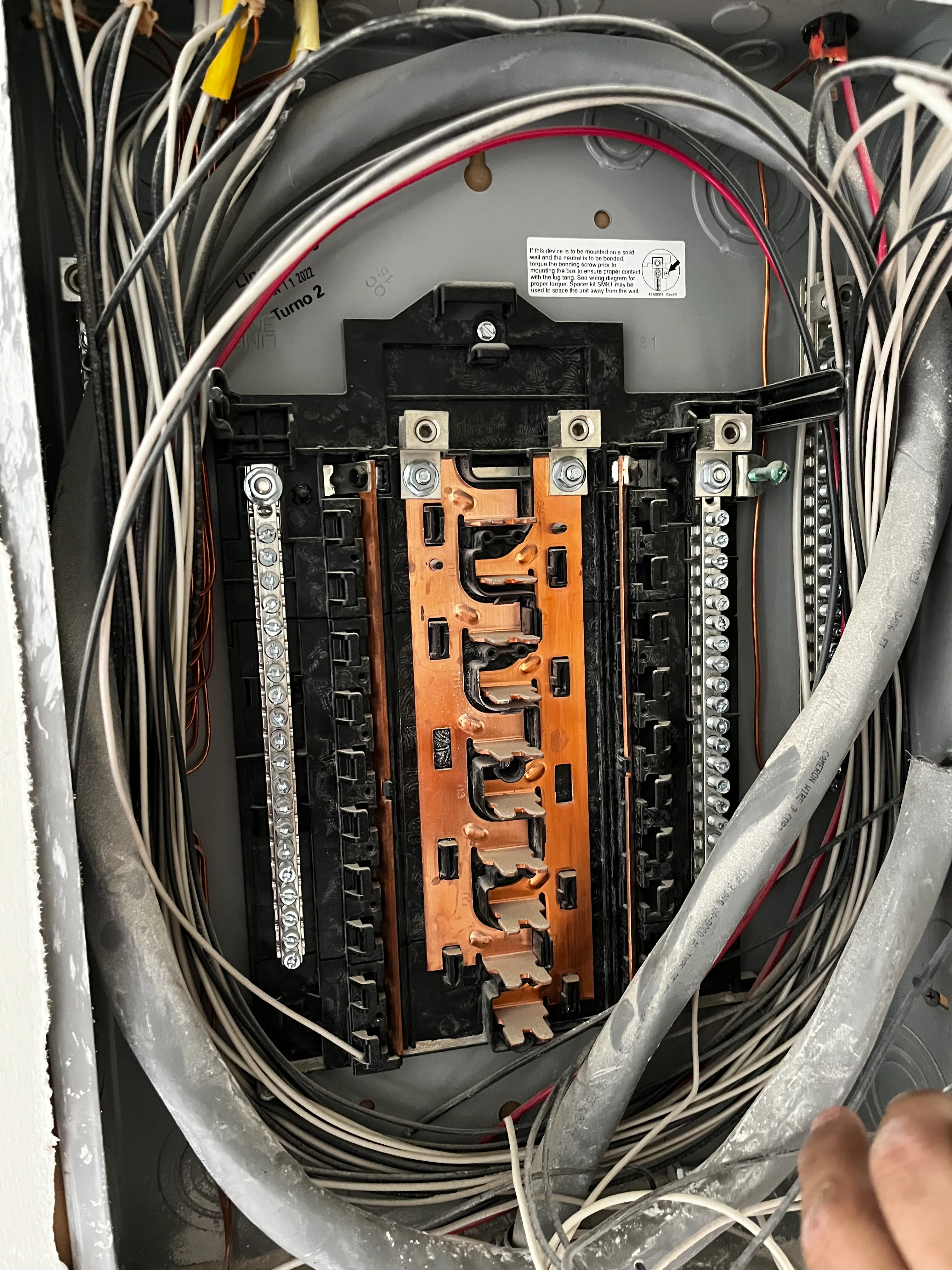 Electrical panel with orange bus bars, black breakers, and organized wiring installation
