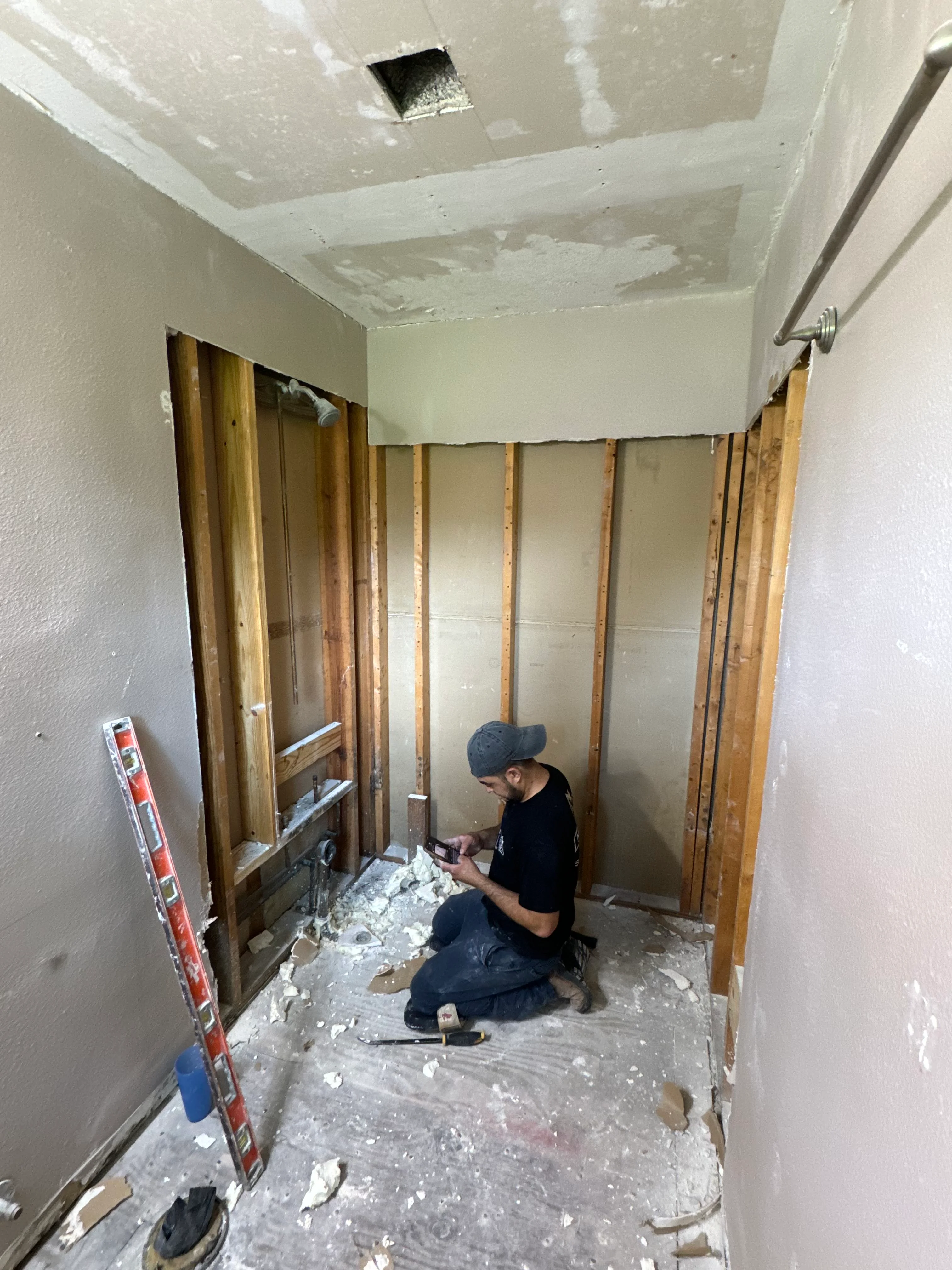 Bathroom renovation in progress with framed walls, drywall installation, and recessed lighting rough-in