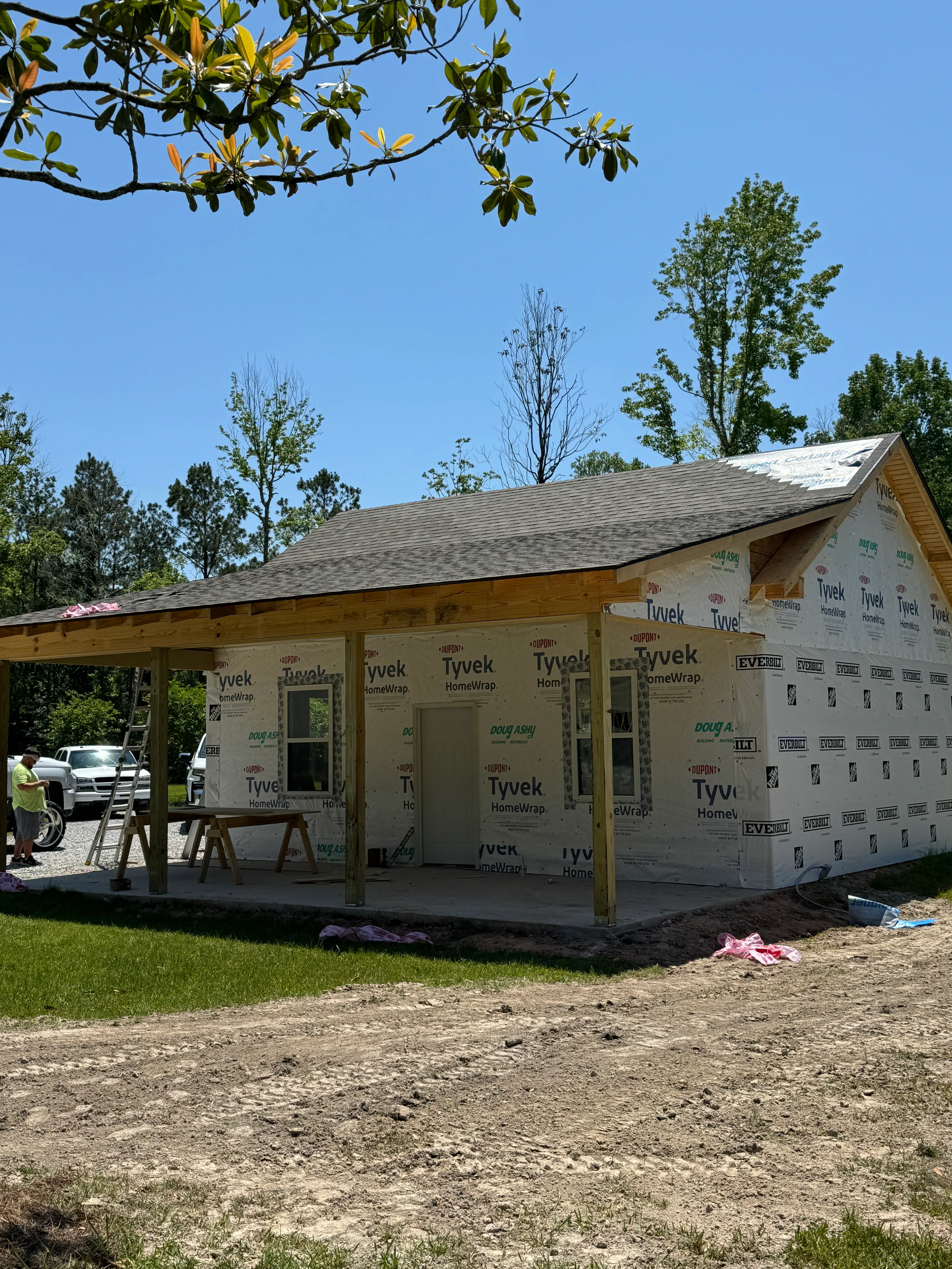 New home construction with timber framing, Tyvek wrap, and completed roof structure