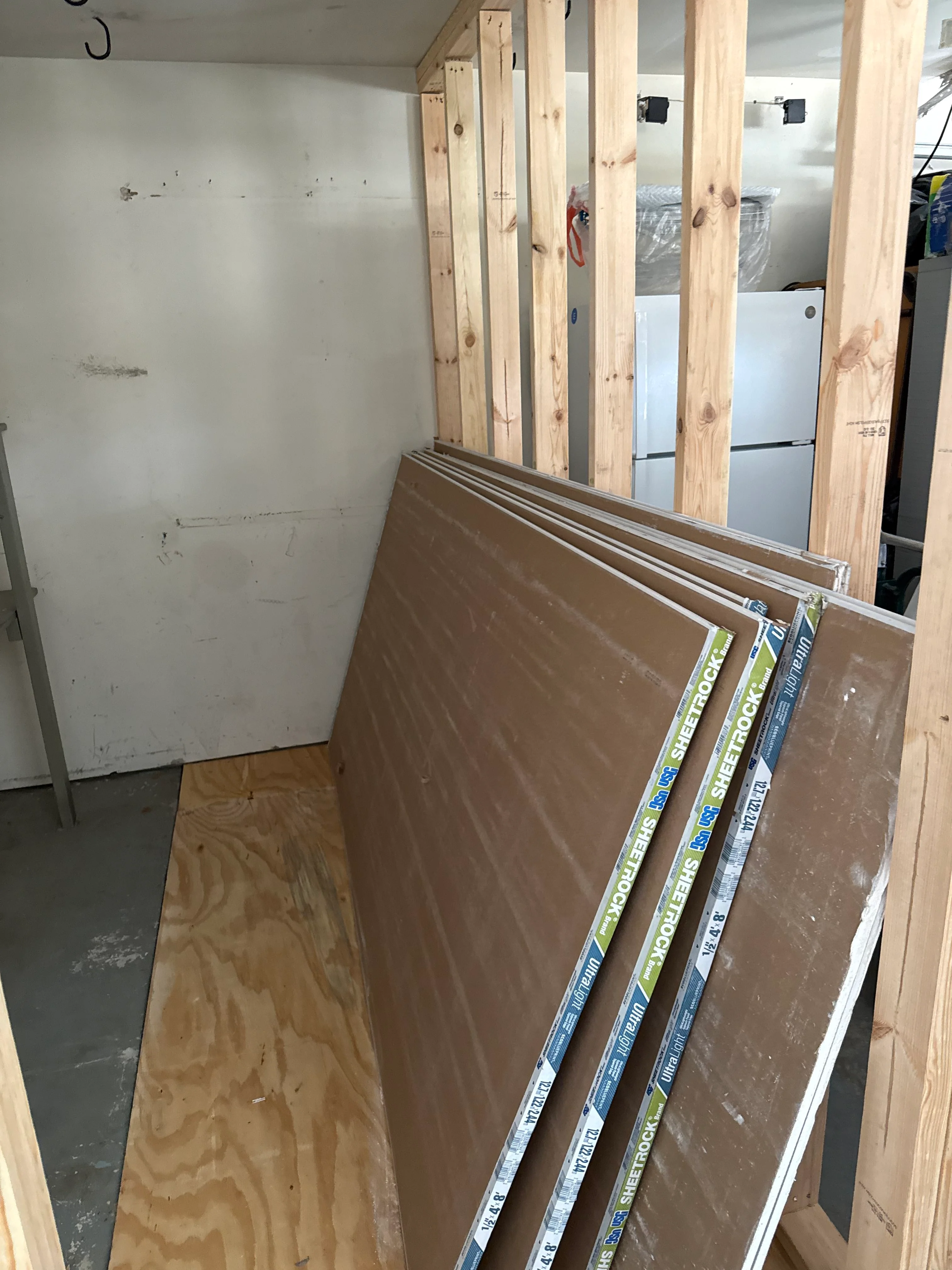 Interior framing with wooden studs and stacked drywall sheets ready for installation