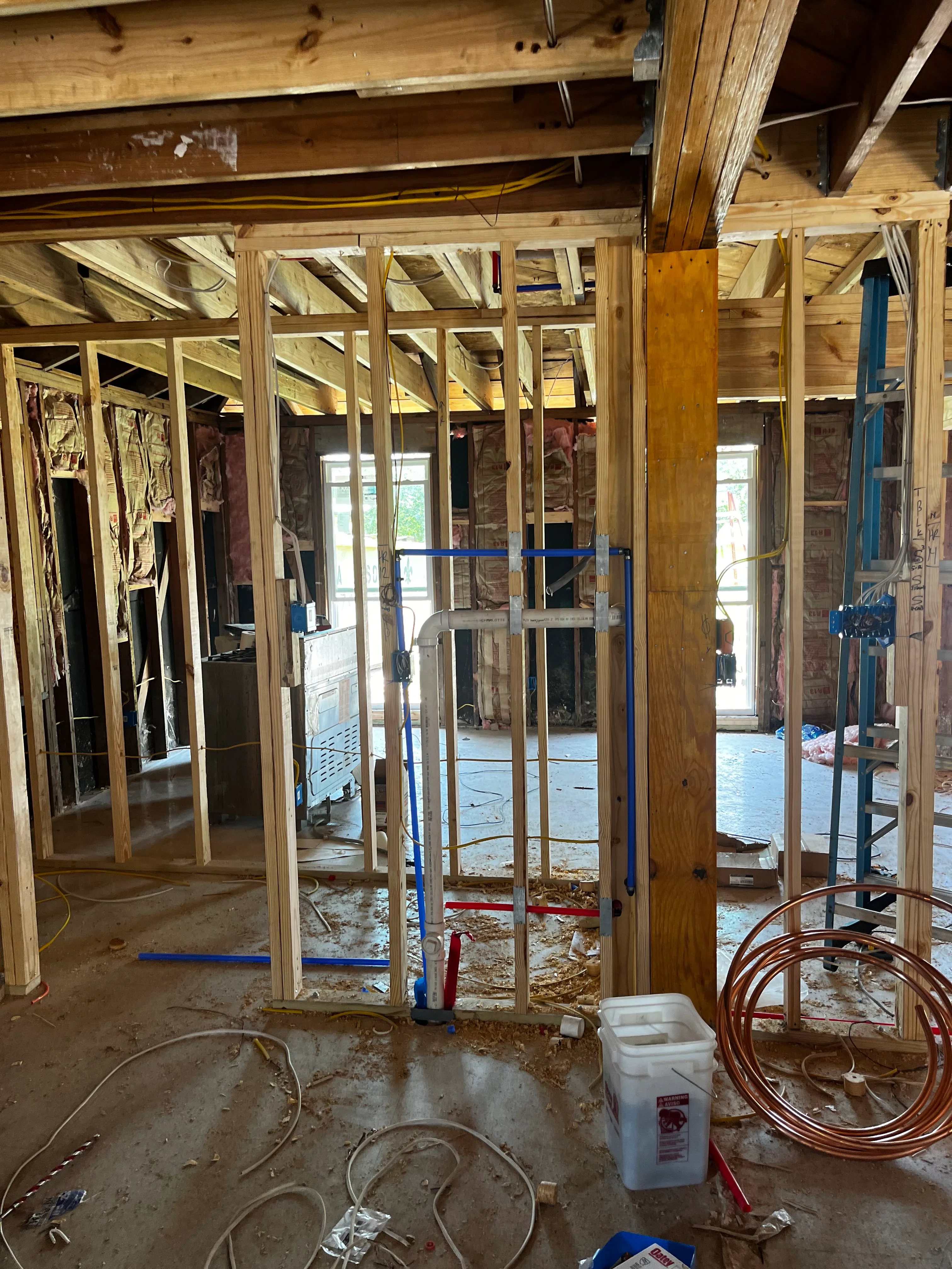 Interior framing with wooden studs, door frames, and electrical/plumbing rough-in materials