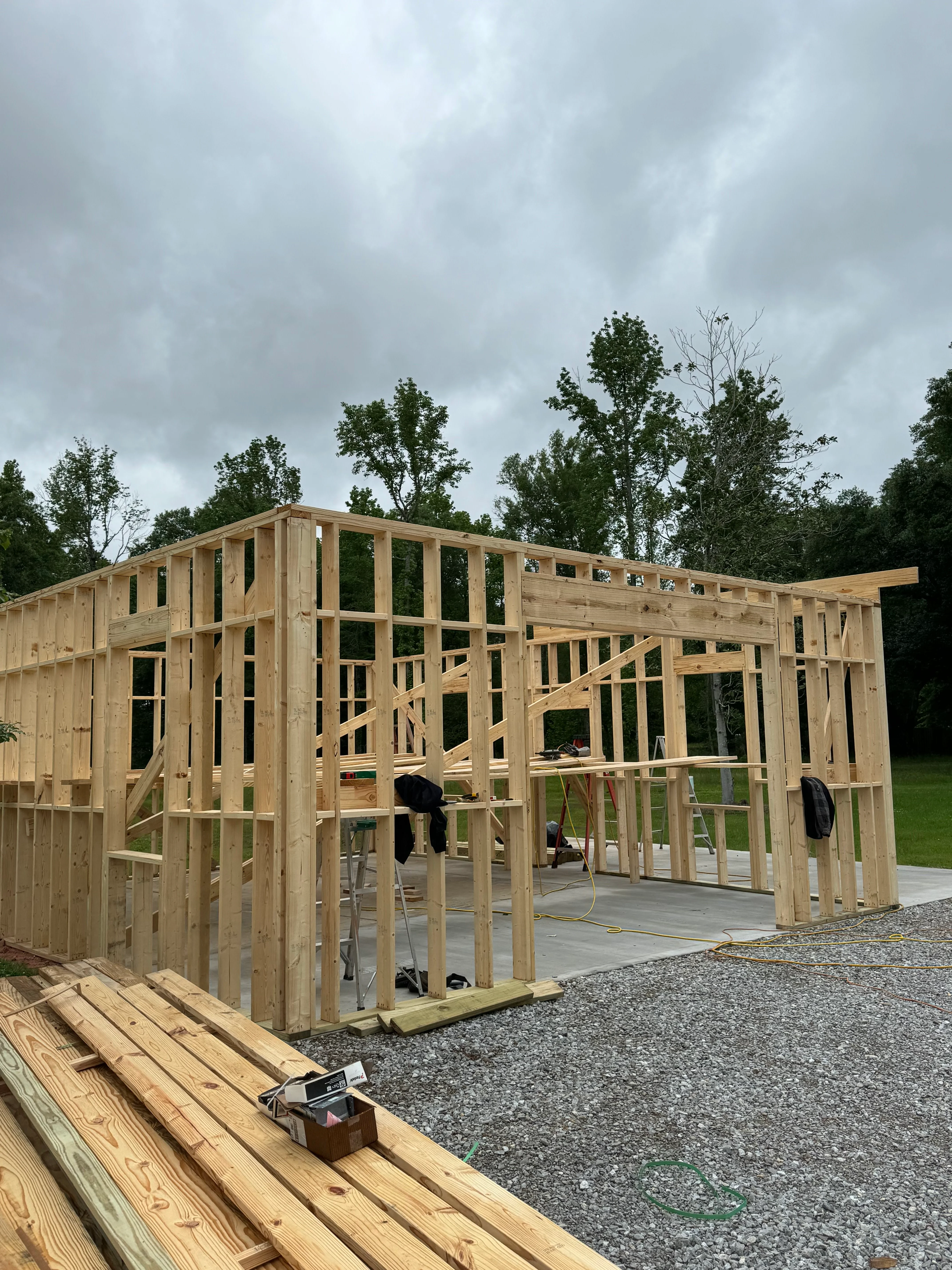 Wood-framed residential construction with open walls showing framing, windows, and concrete foundation