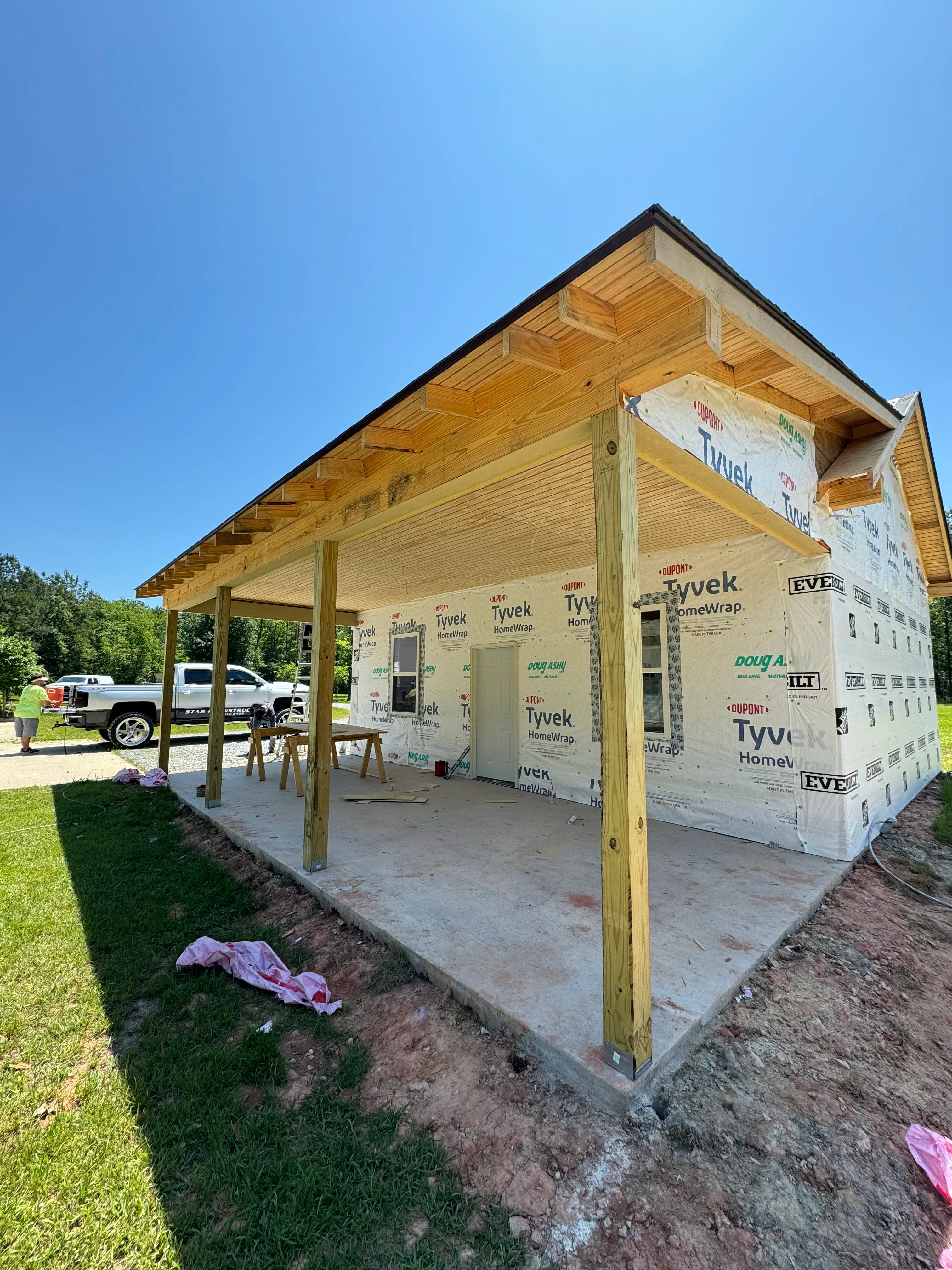 Wood-framed residential addition with covered porch and Tyvek wrap during construction