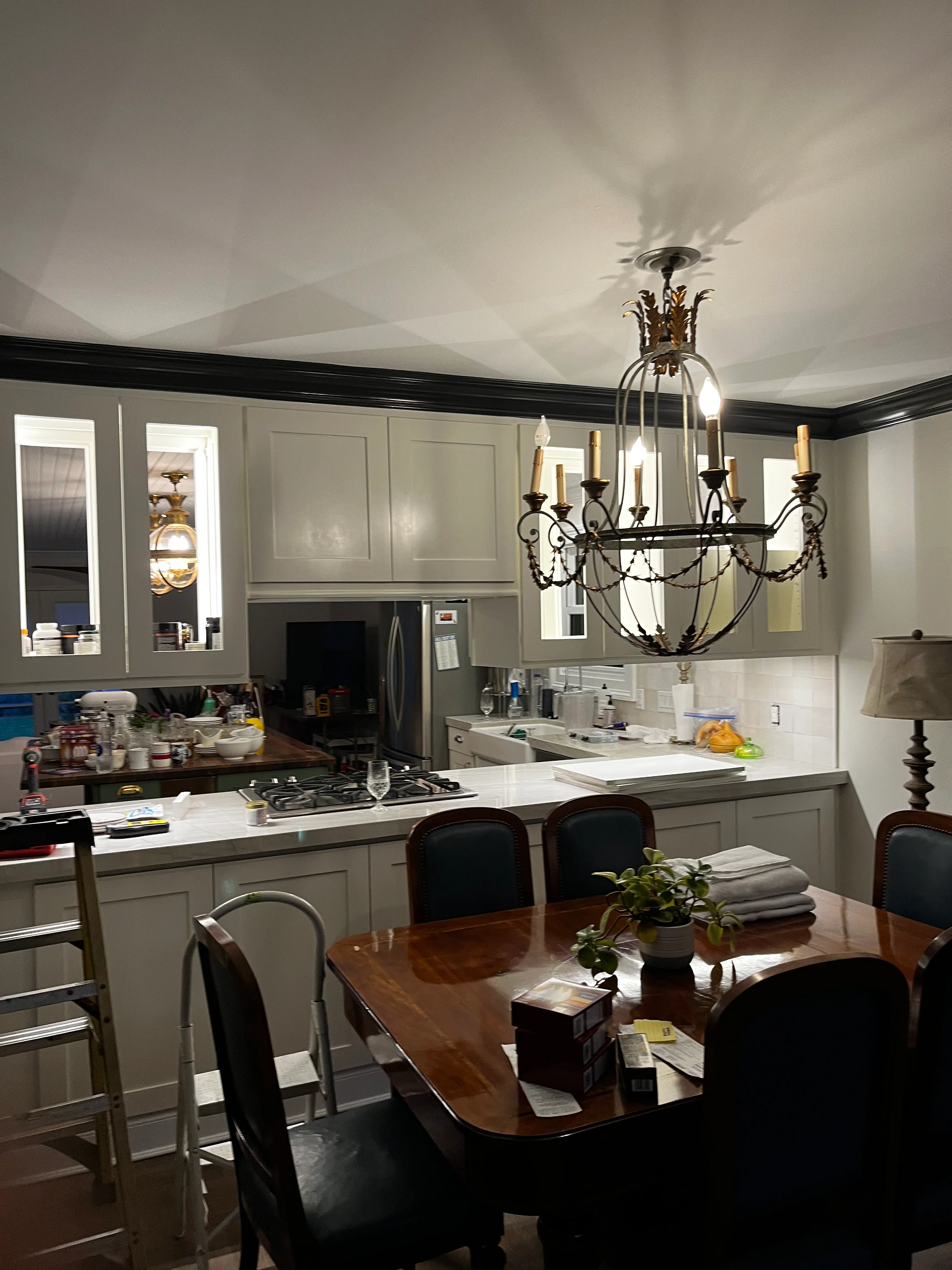 Modern kitchen with gray cabinetry, white tile, and elegant dining area with chandelier
