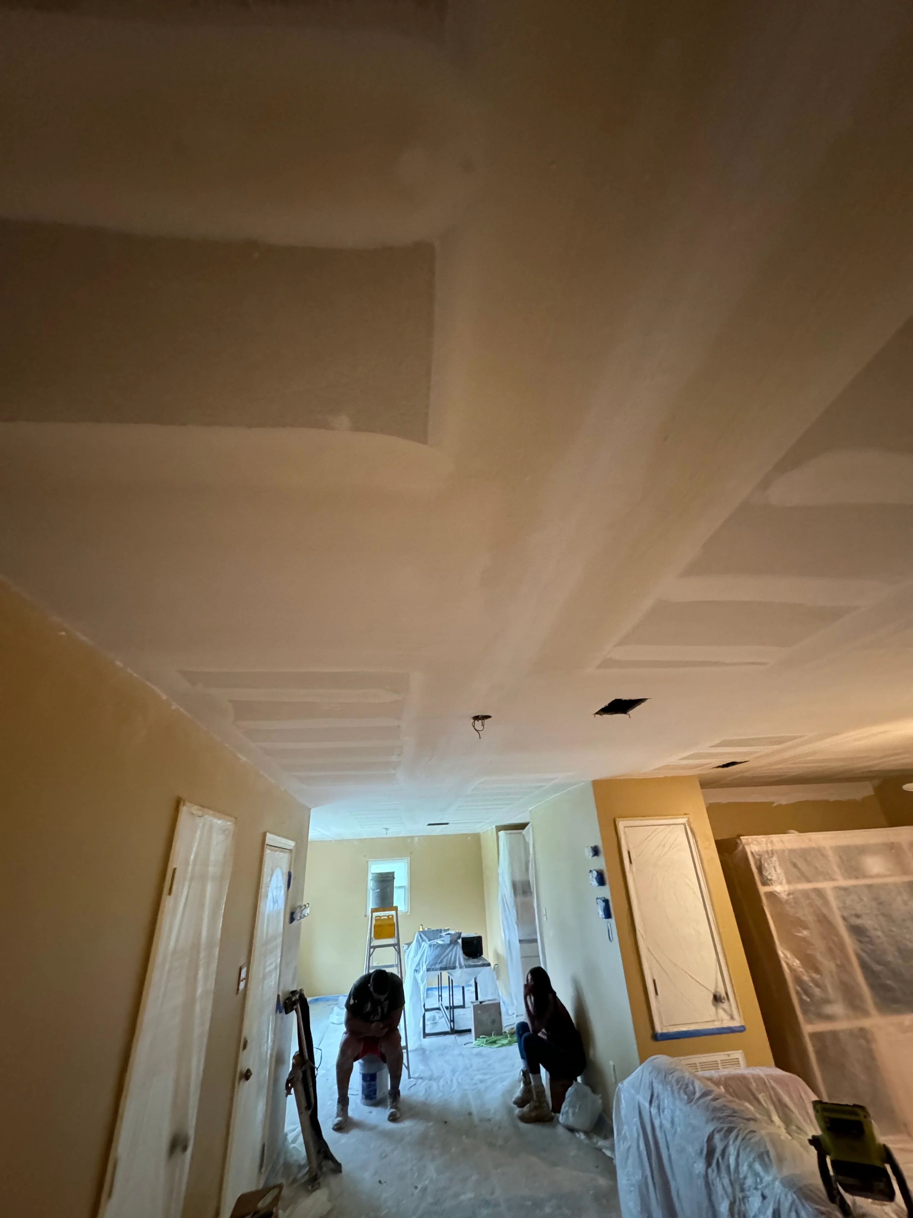 Interior drywall installation with finished ceiling and recessed lighting in residential renovation