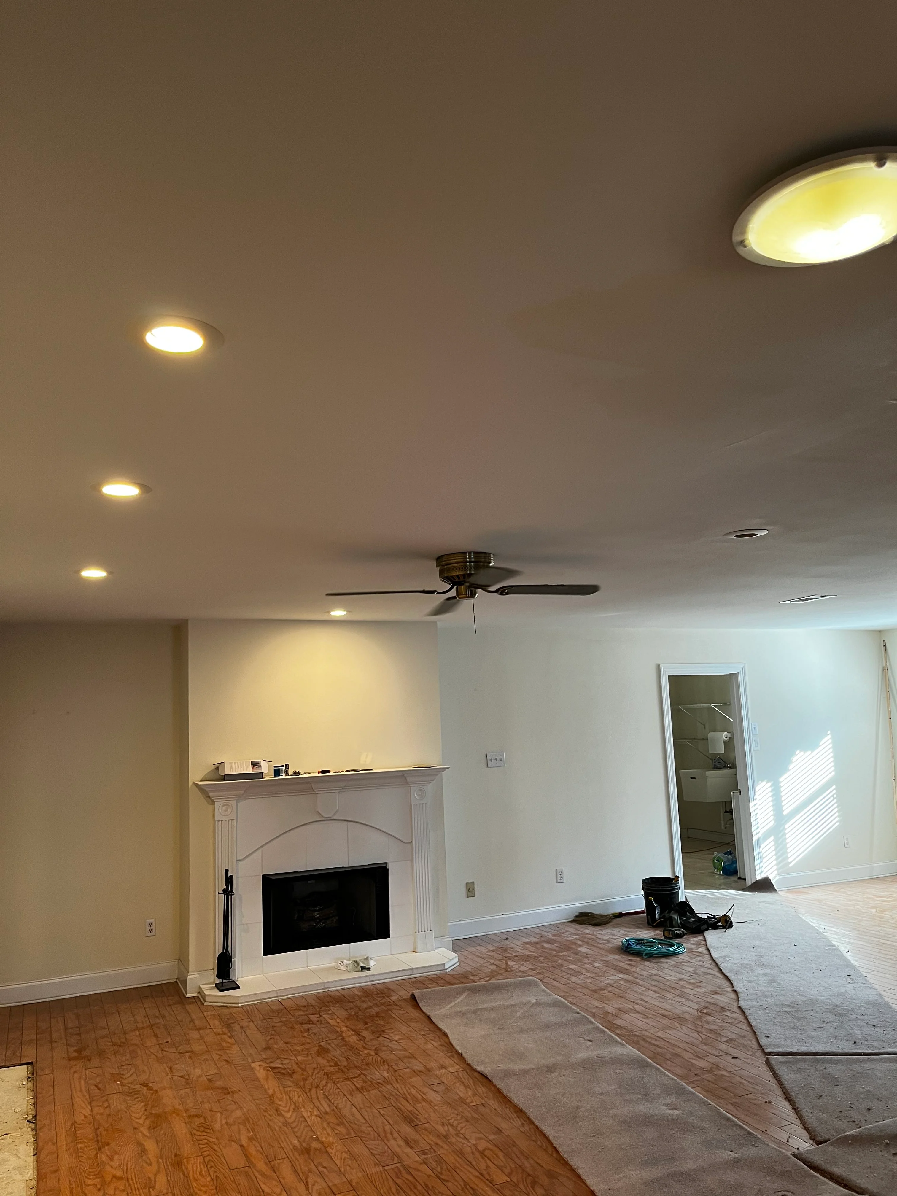 Renovated living room with recessed ceiling lights, fireplace, and ceiling fan installation