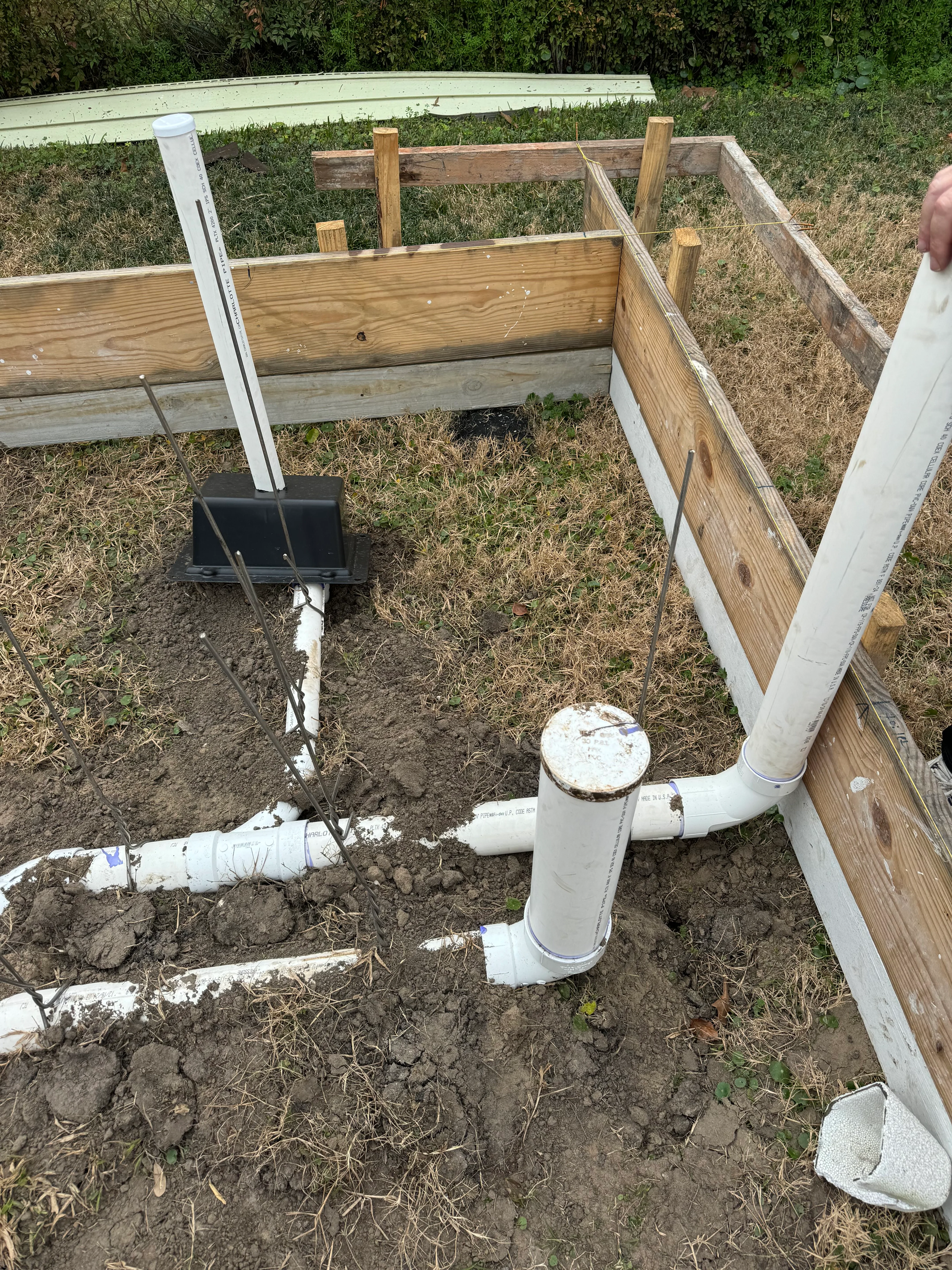 Overhead view of wooden raised garden beds with installed PVC drainage system and collection basin