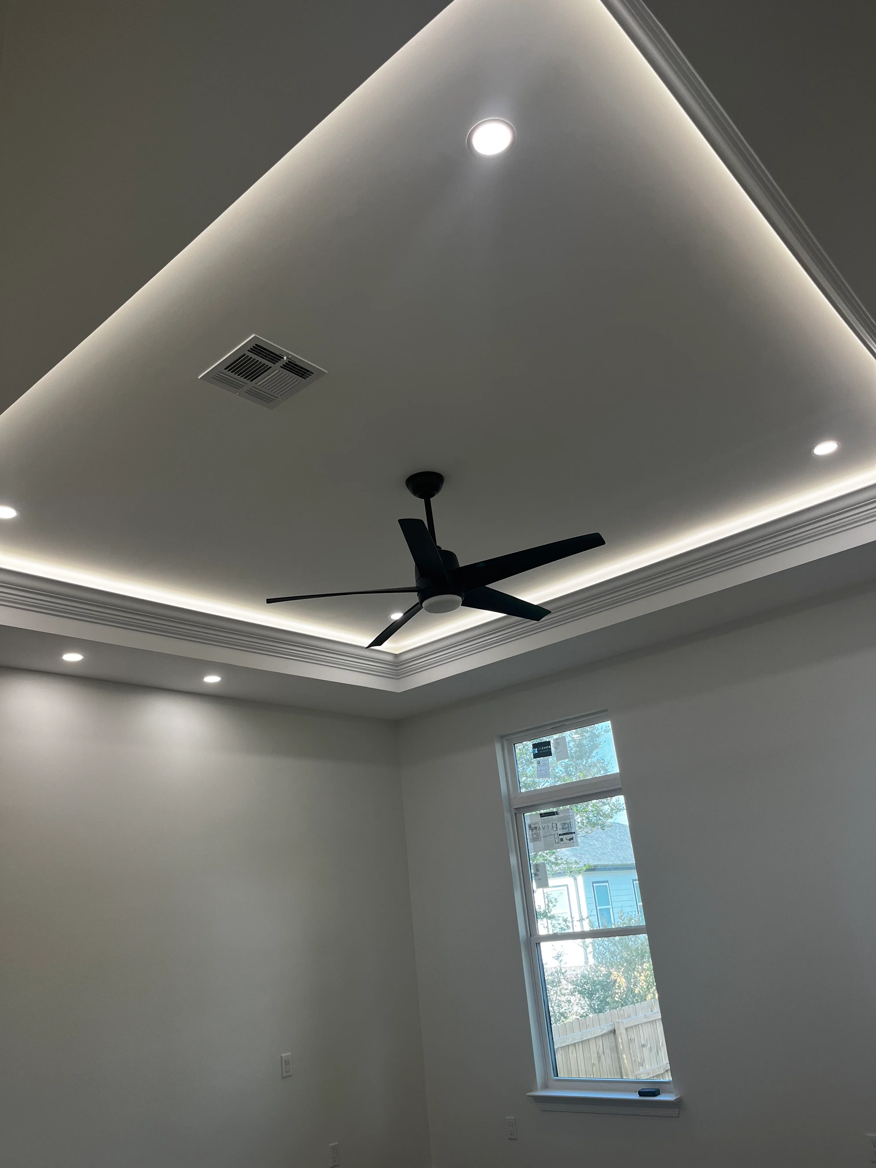 Modern white tray ceiling with LED lighting, recessed fixtures, and black ceiling fan