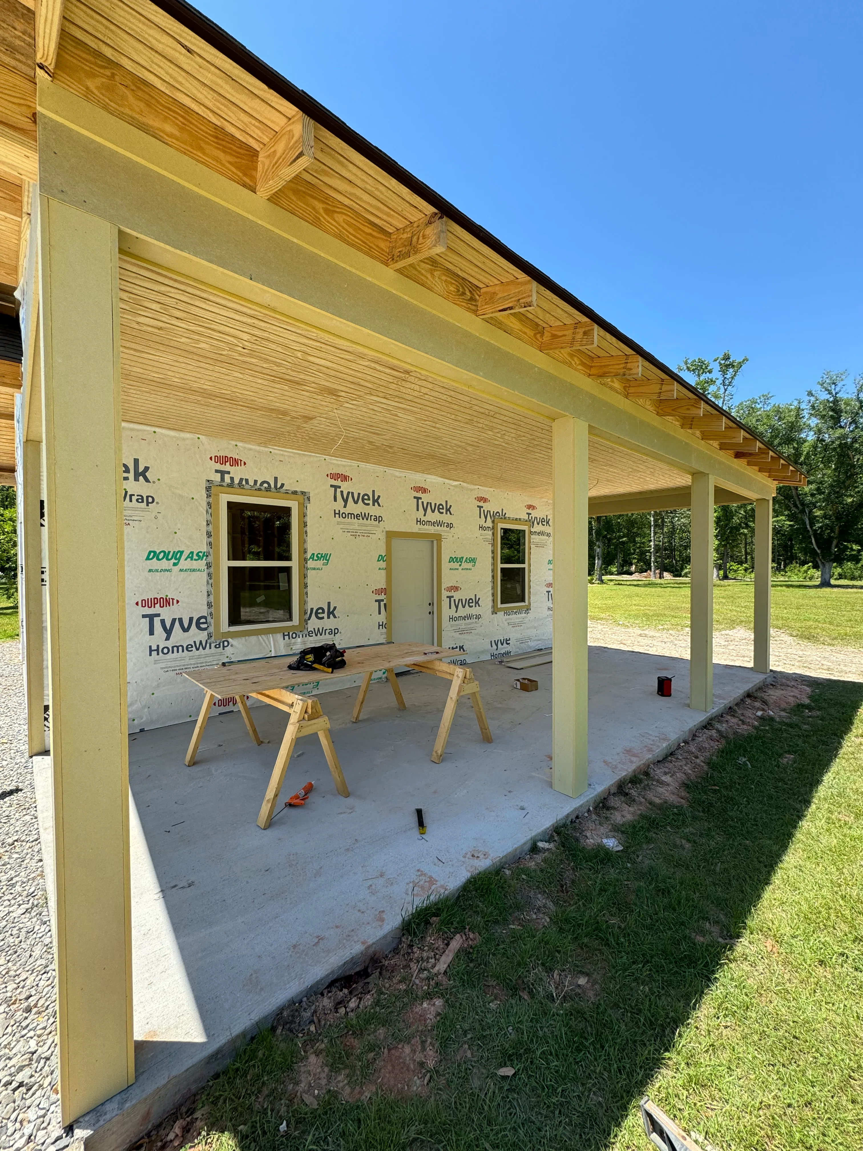 Residential addition under construction with wood framing, Tyvek wrap, and concrete foundation
