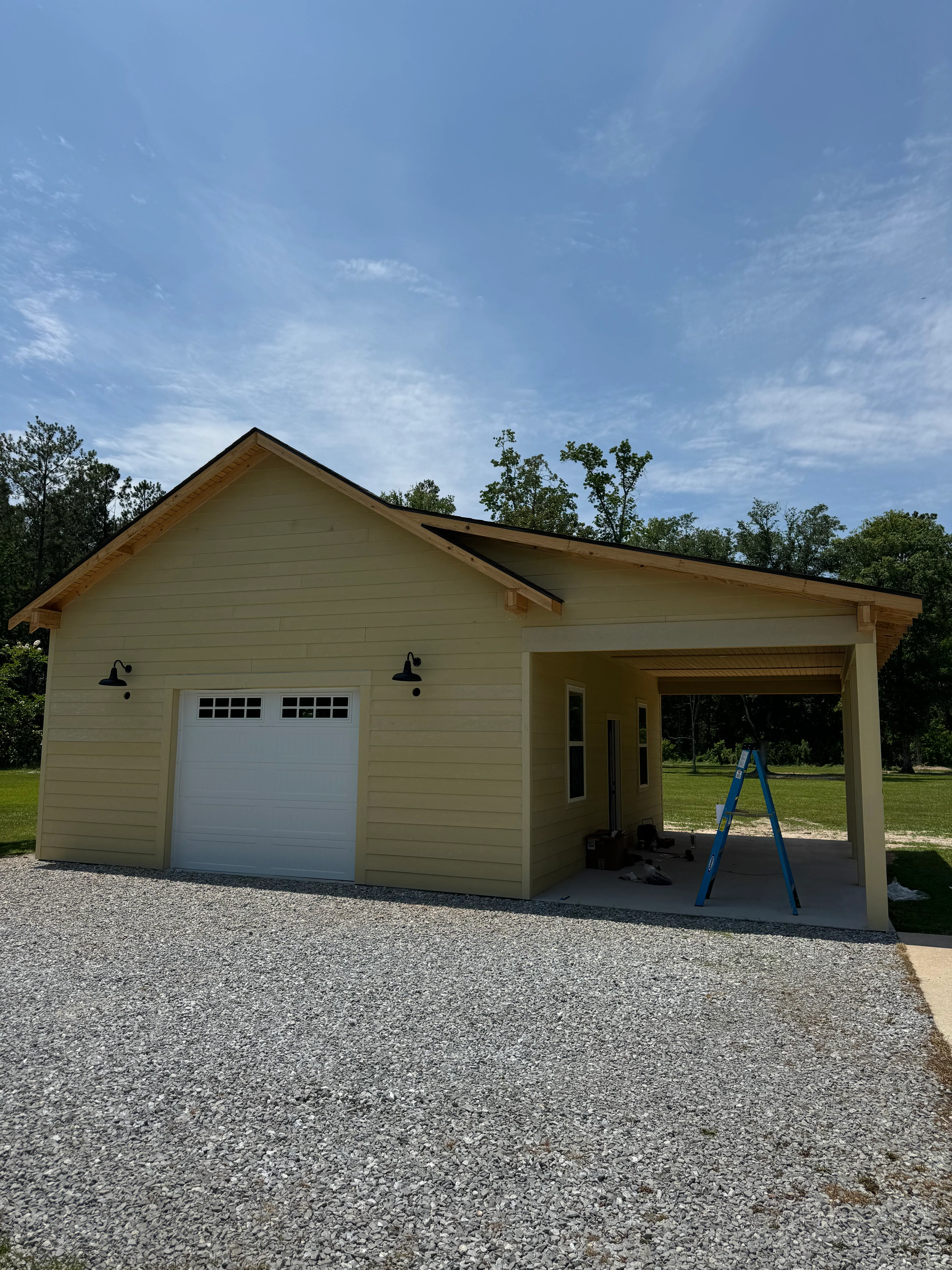 Newly constructed cream-colored garage with white door and covered carport extension