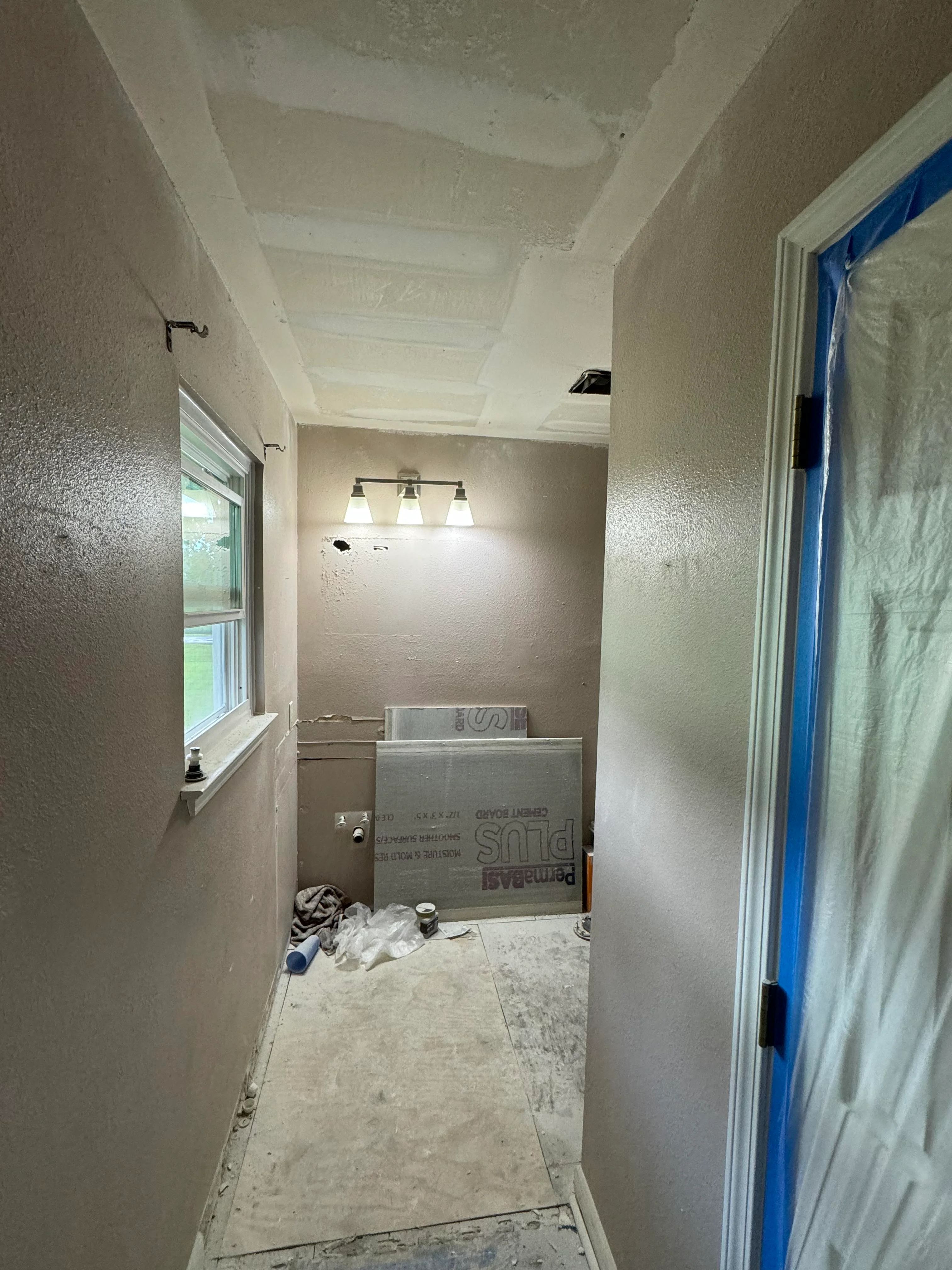 Bathroom under renovation with drywall installation, vanity cabinet, and ceiling work