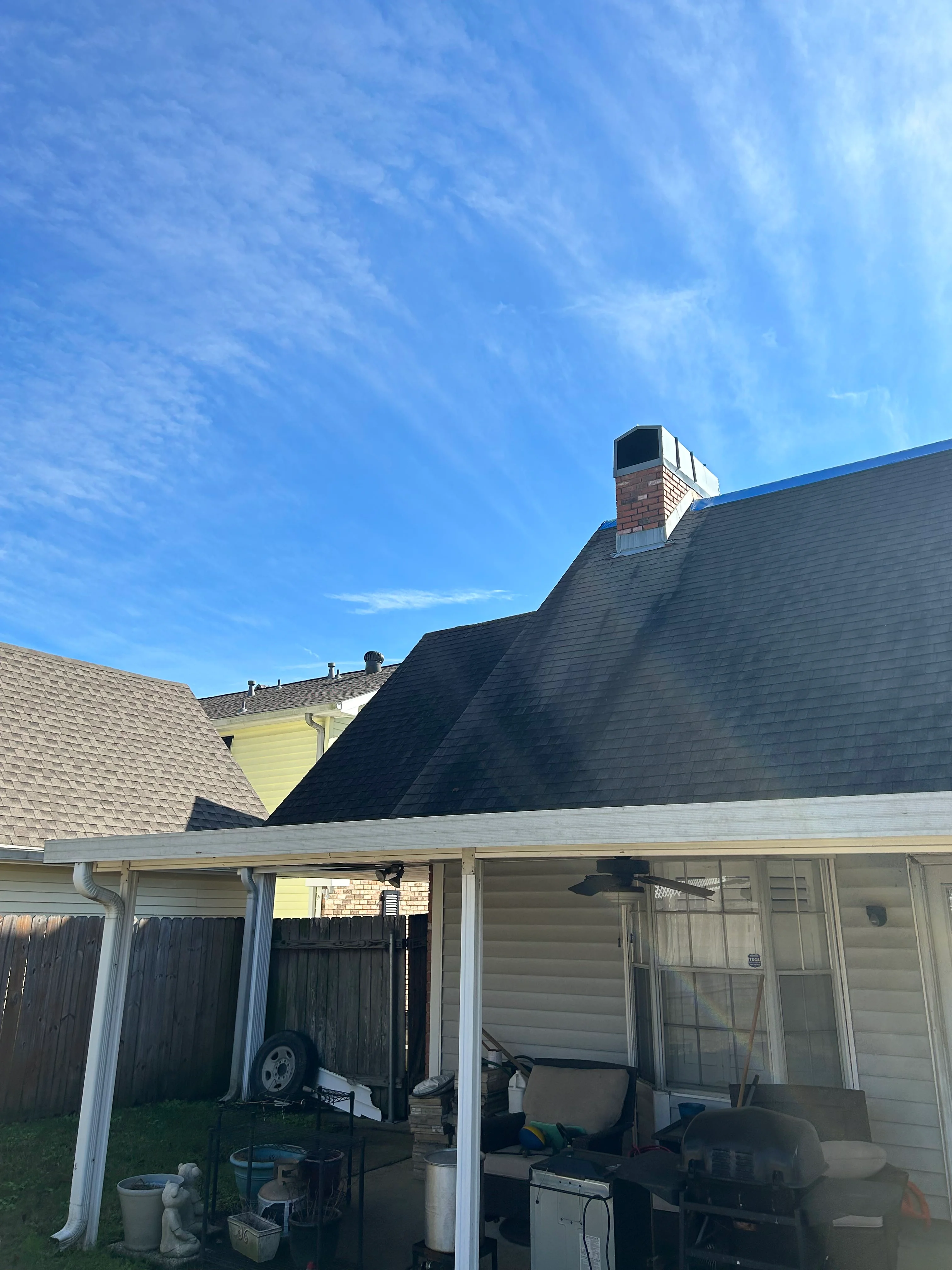 New residential roof with charcoal architectural shingles, brick chimney, and white soffit
