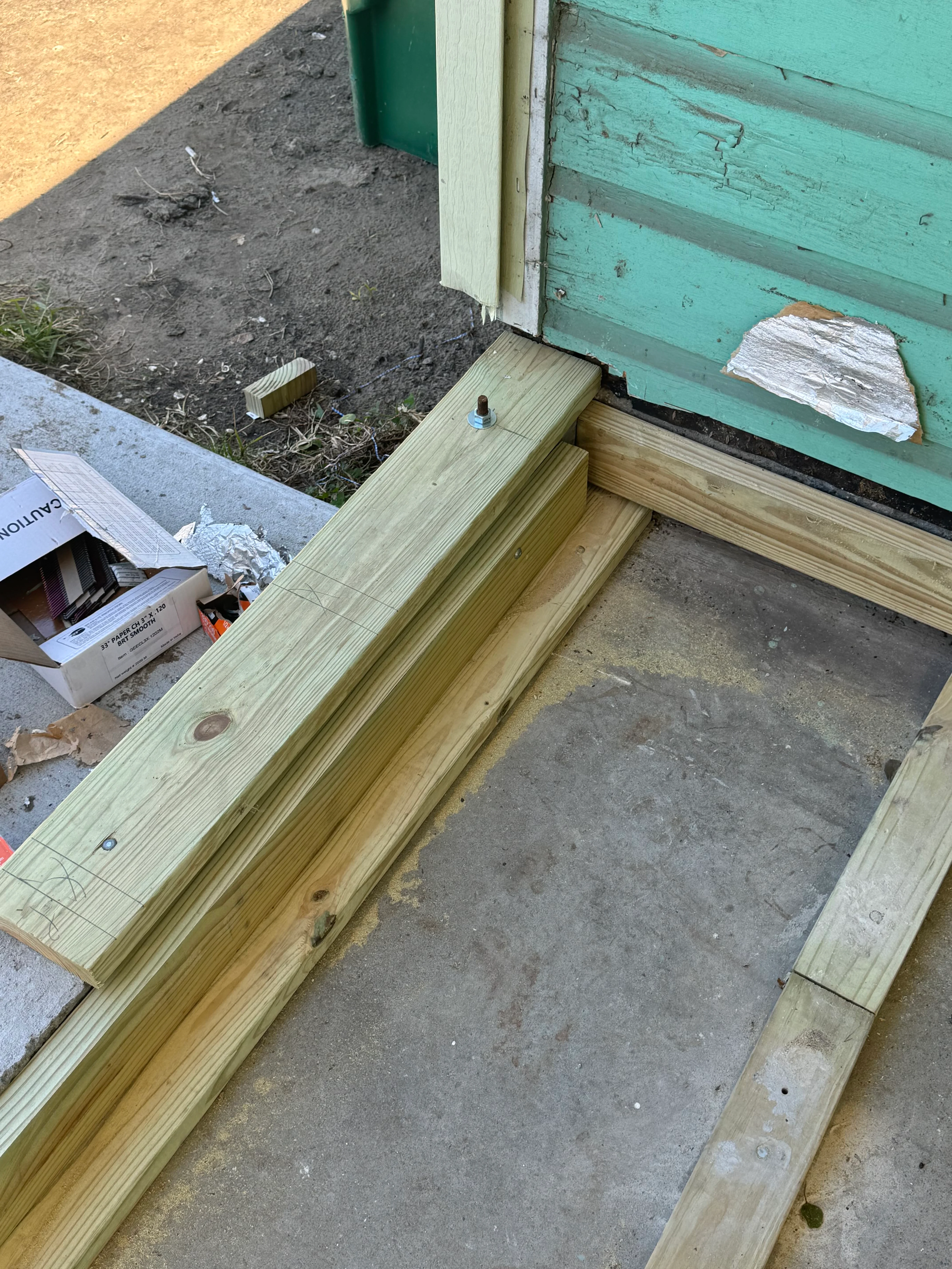 Pressure-treated deck framing with rim joists and floor members installed on concrete foundation