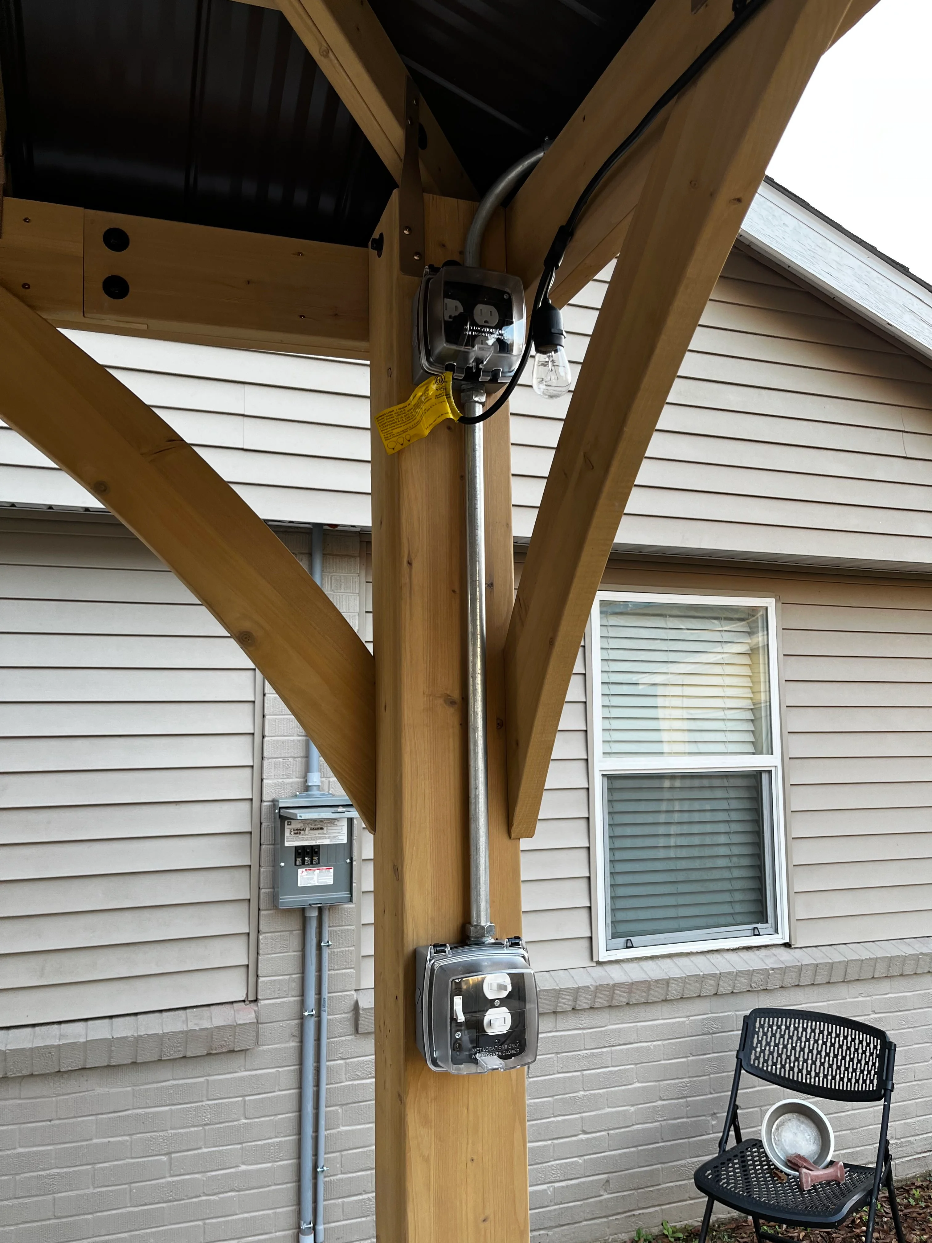 Electrical outlets installed on wooden pergola post with conduit and weatherproof covers