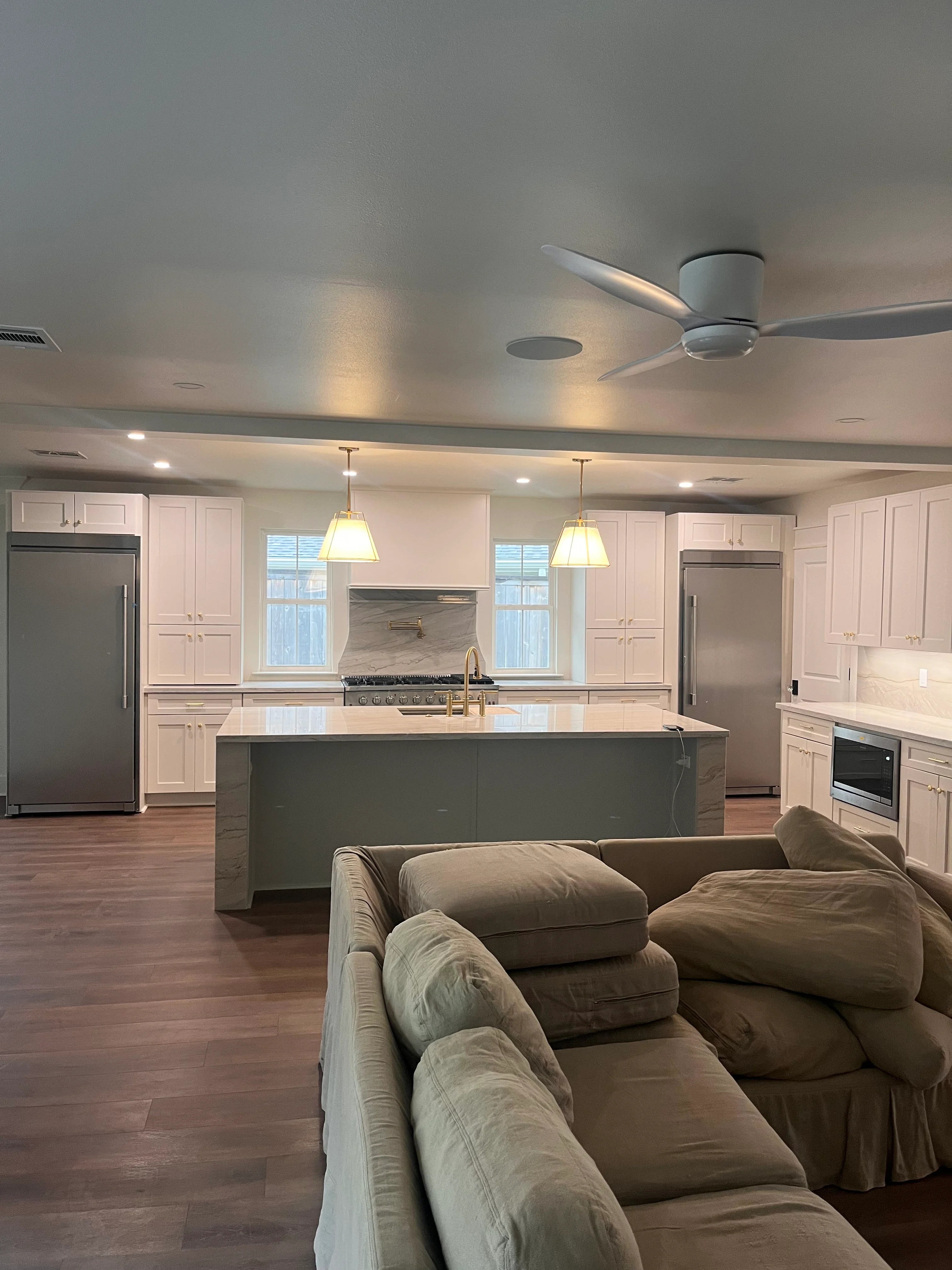 Modern open-concept kitchen with white cabinetry, dark island, and integrated living space