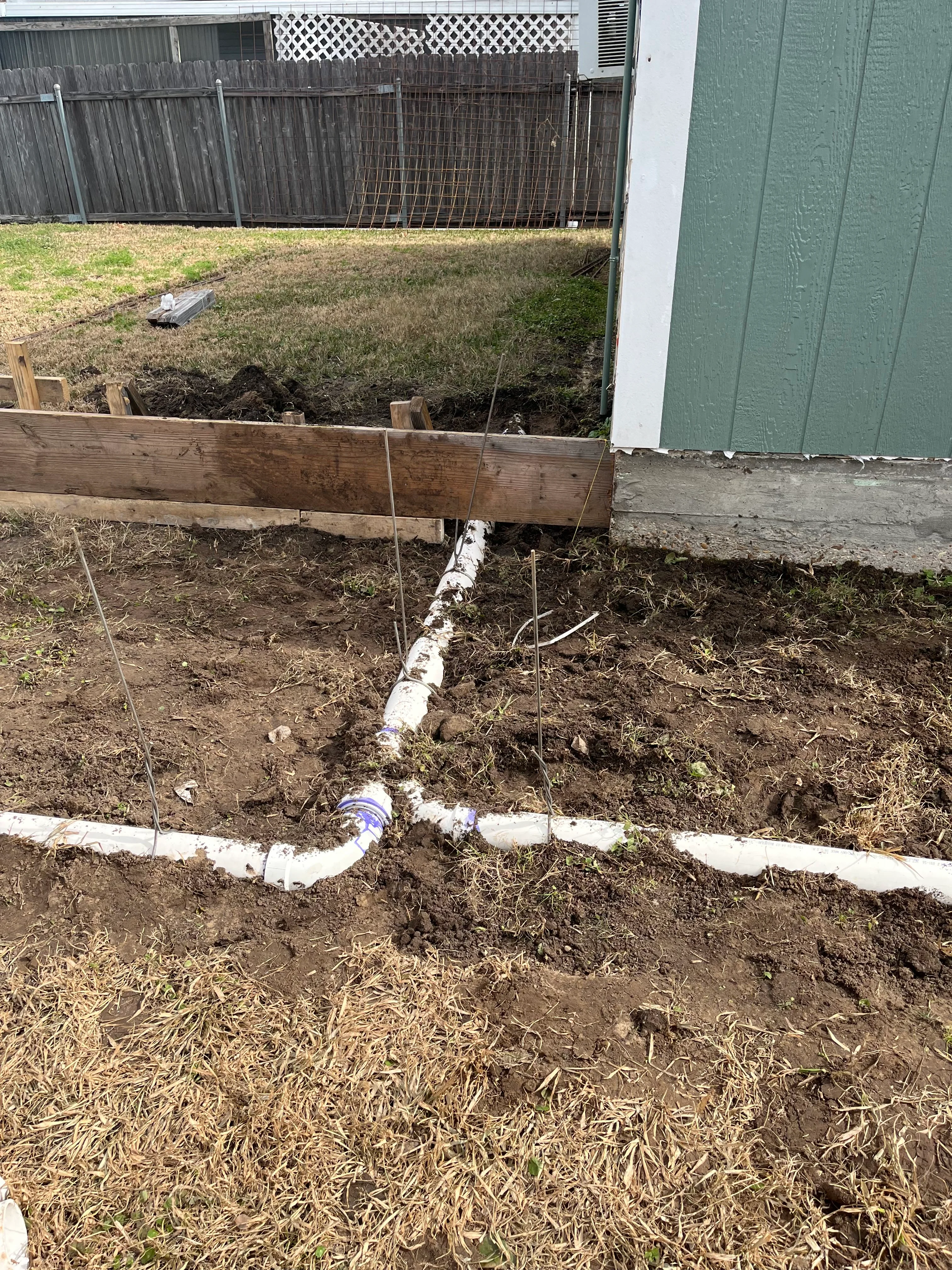 Residential drainage installation with PVC pipes and graded soil in New Orleans backyard