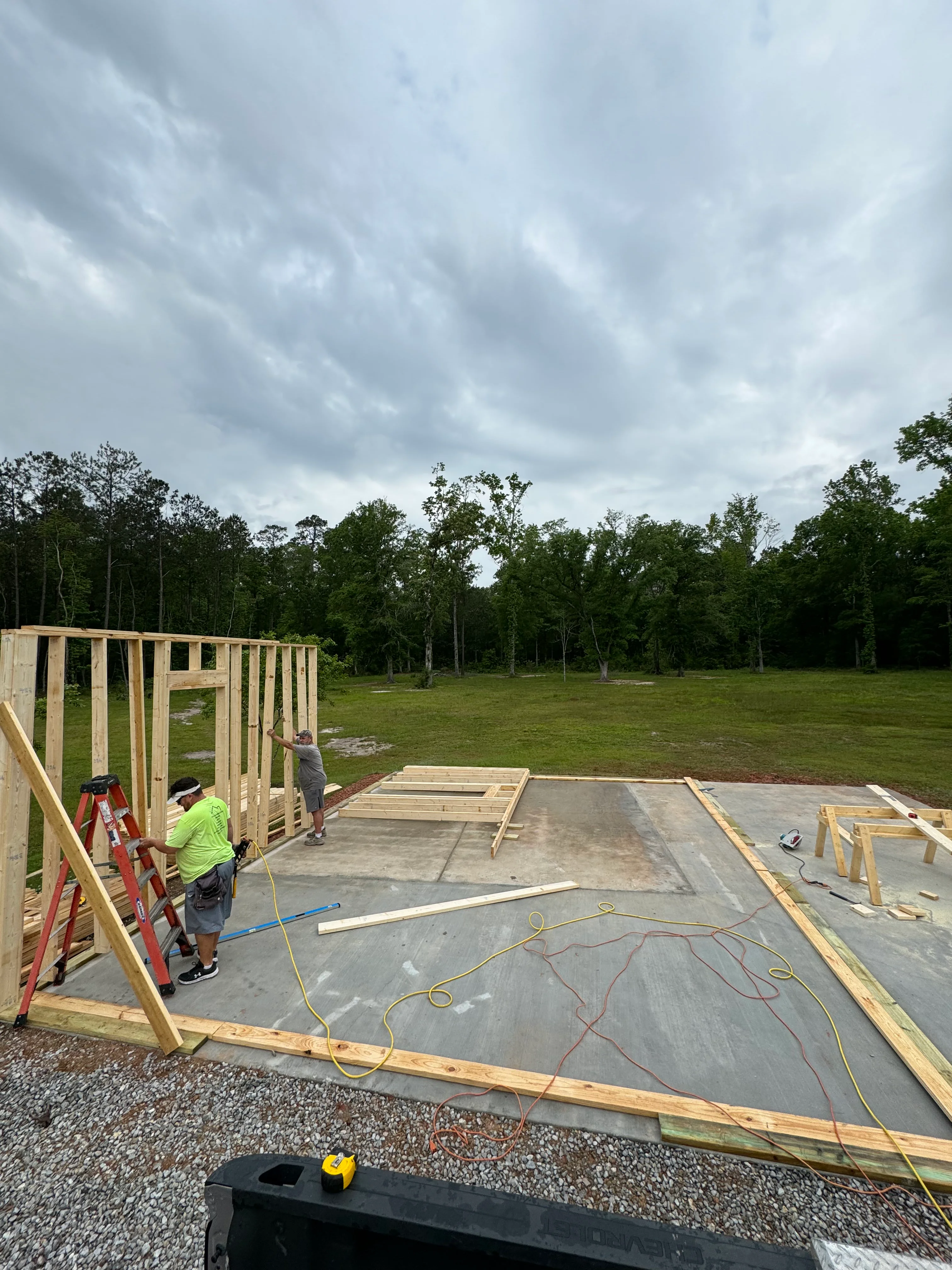 Residential construction site with concrete foundation and wooden wall framing in progress