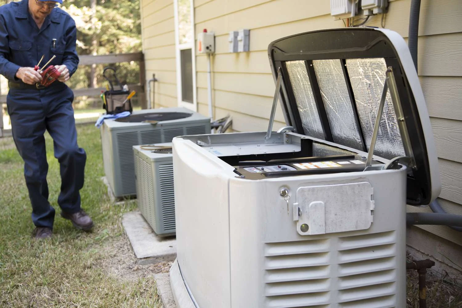 Technician servicing whole house generator installed next to HVAC units
