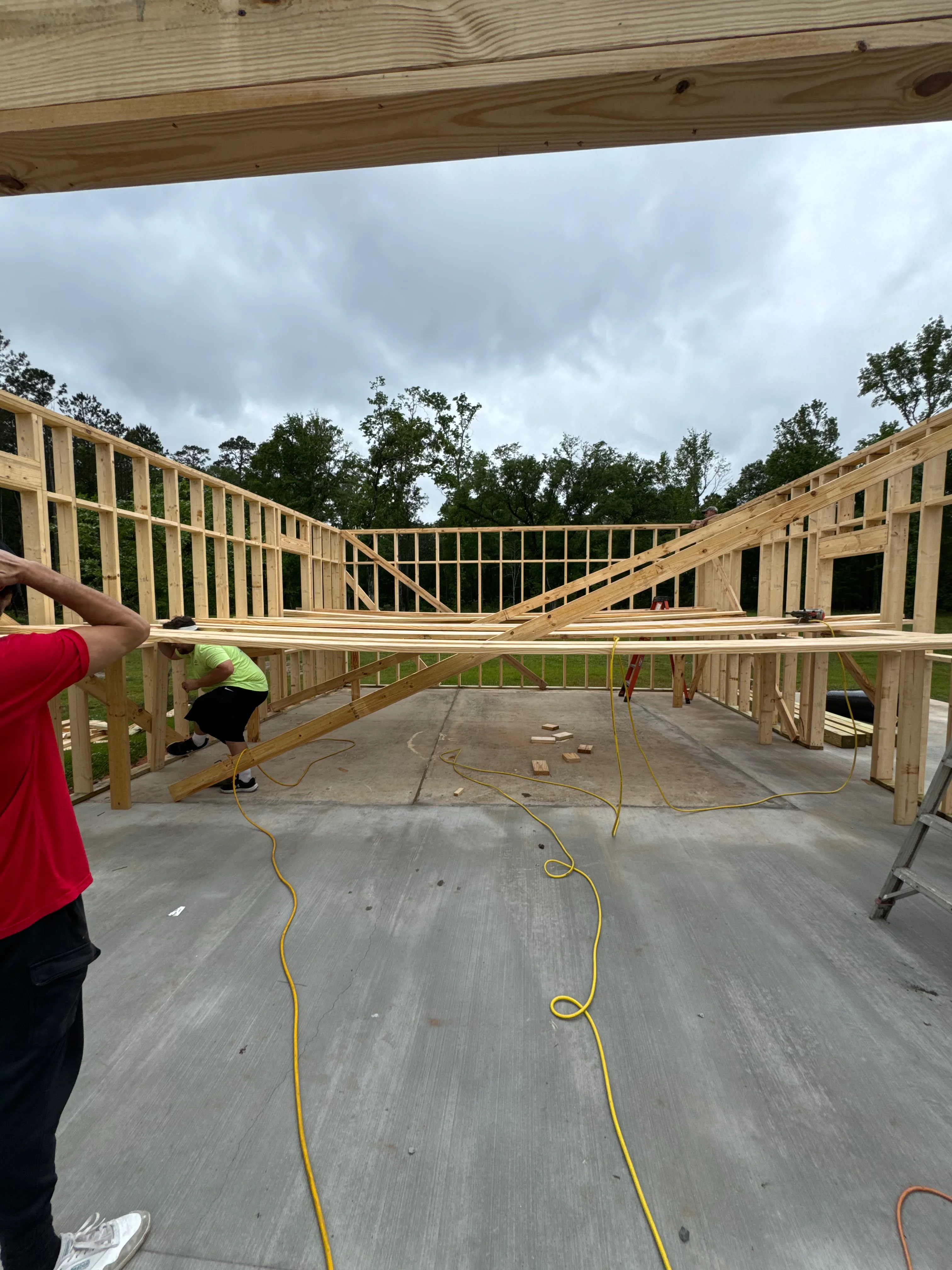 Interior framing of residential construction with wood walls, roof trusses, and concrete floor