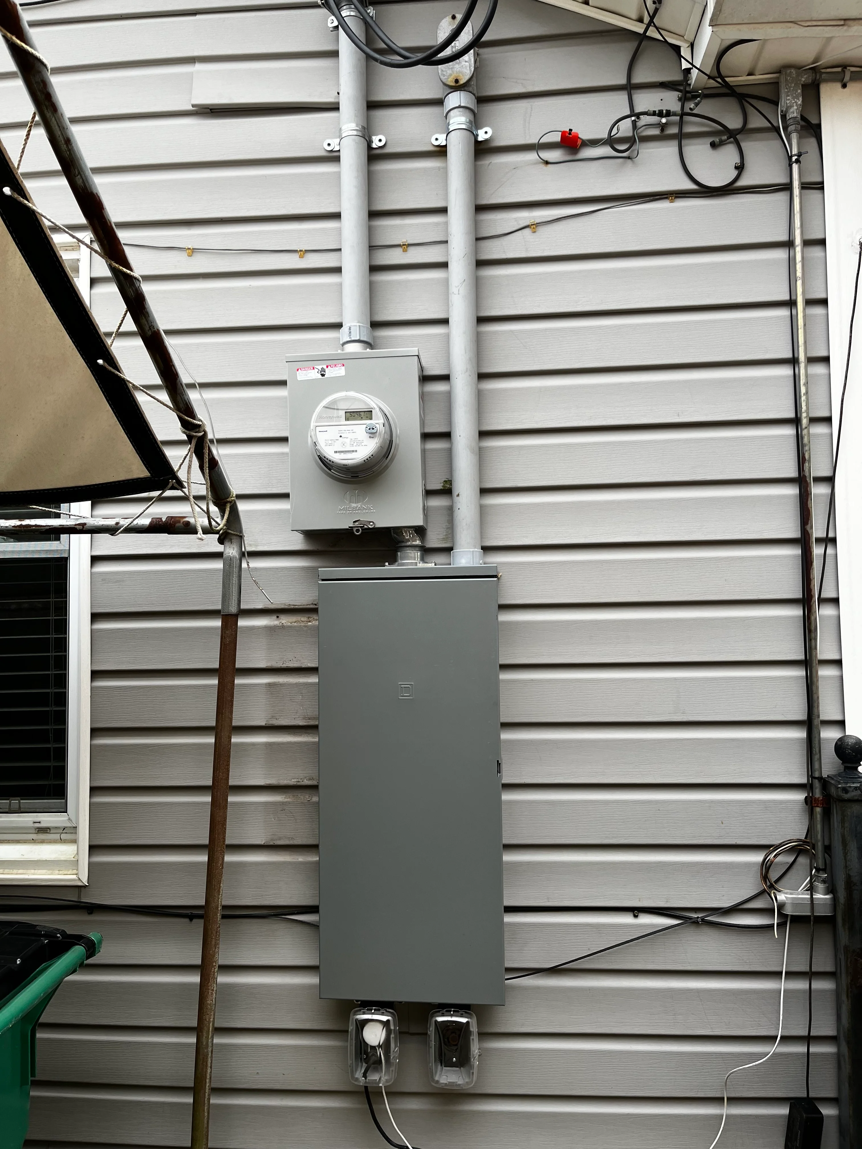 Electrical service panel and meter box installed on metal siding with conduit and wiring