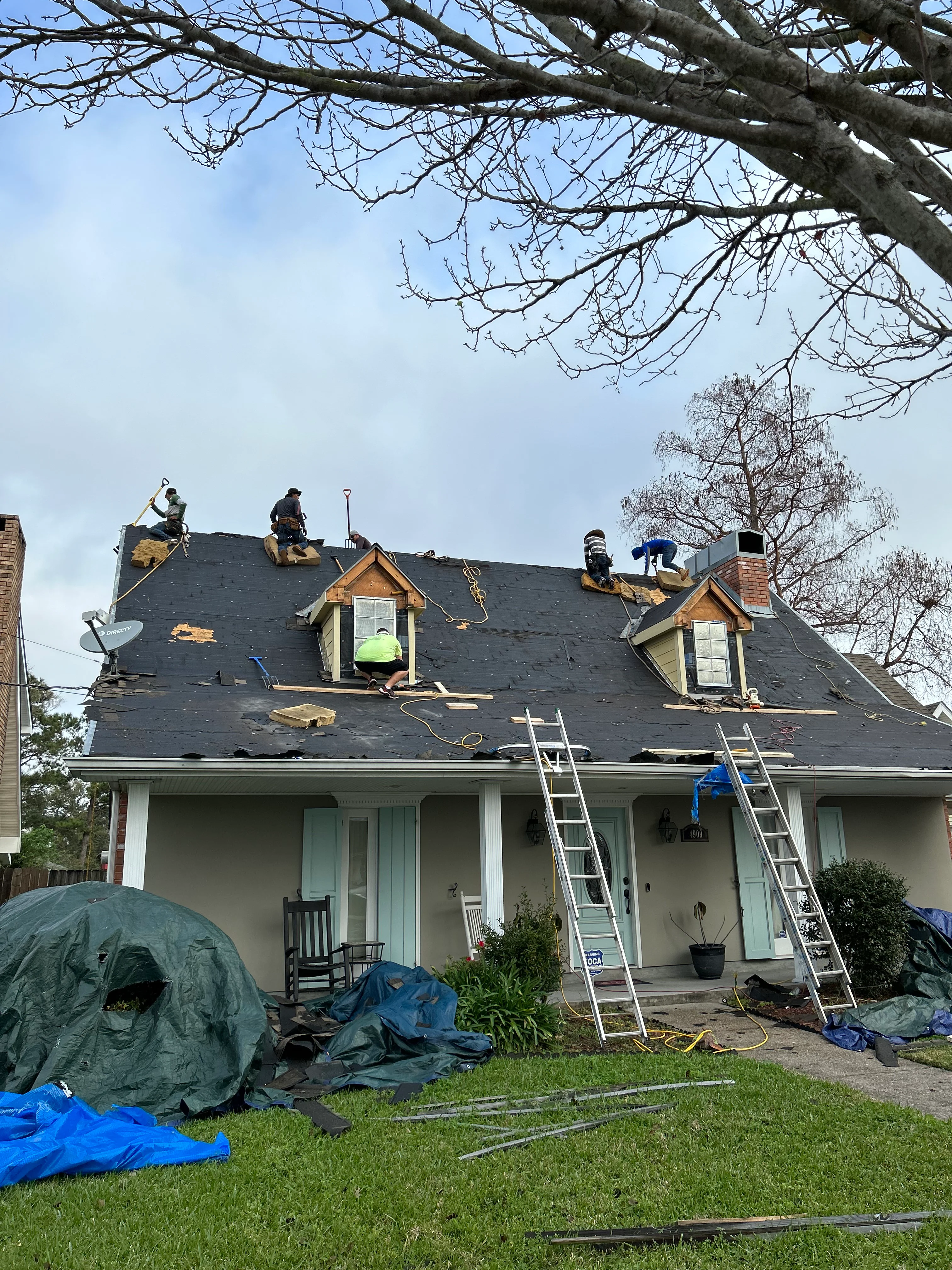 Roofing crew installing new shingles on residential home with dormers in New Orleans