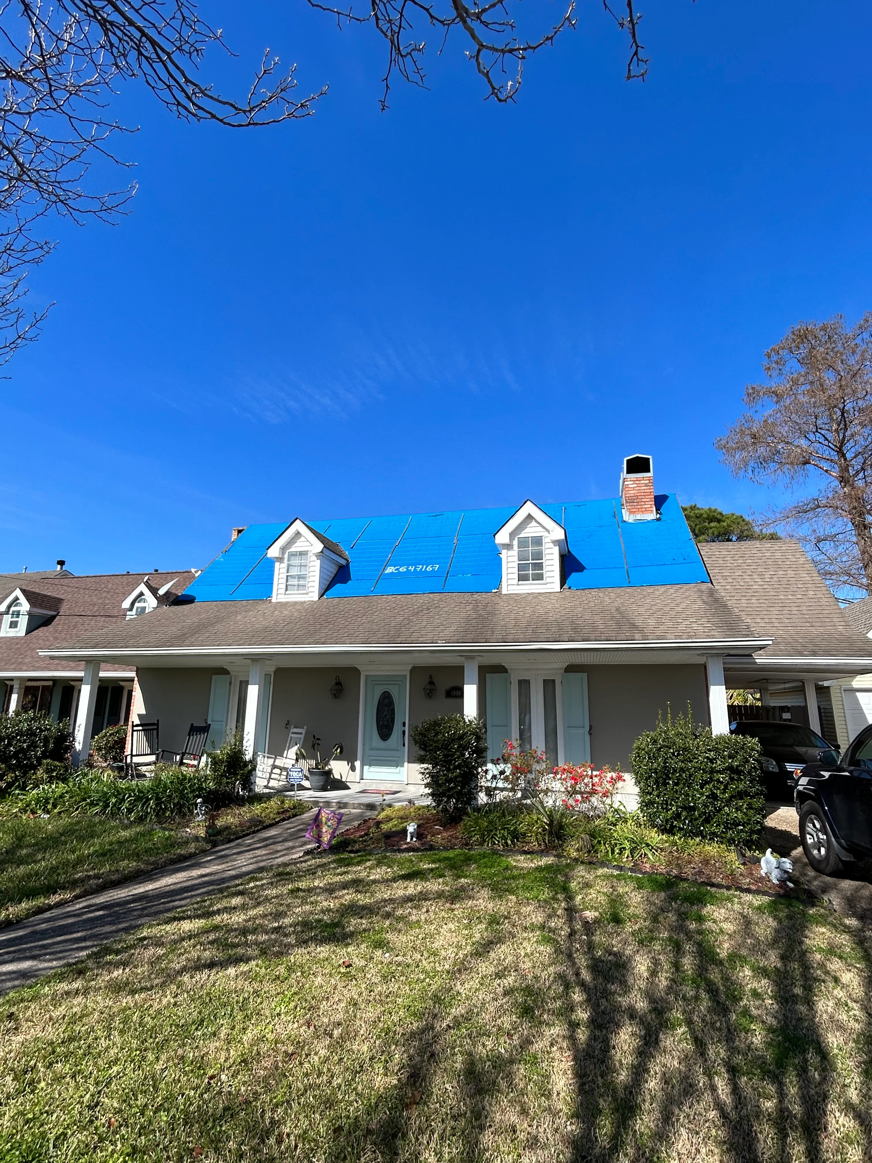 White Cape Cod home with bright blue roof and two dormers, newly installed shingles visible