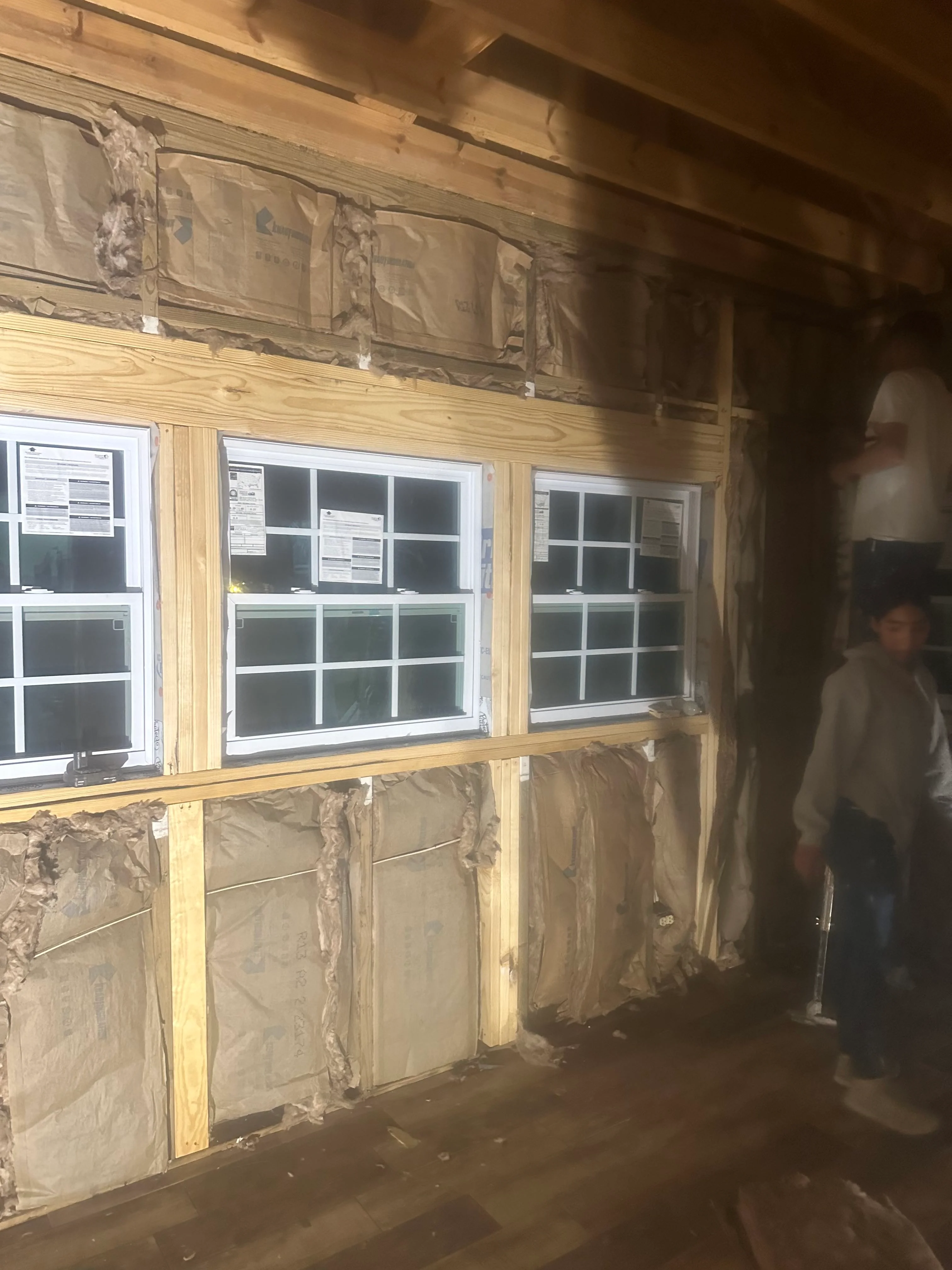 Commercial storefront windows installed in wood frame with insulation and protective coverings