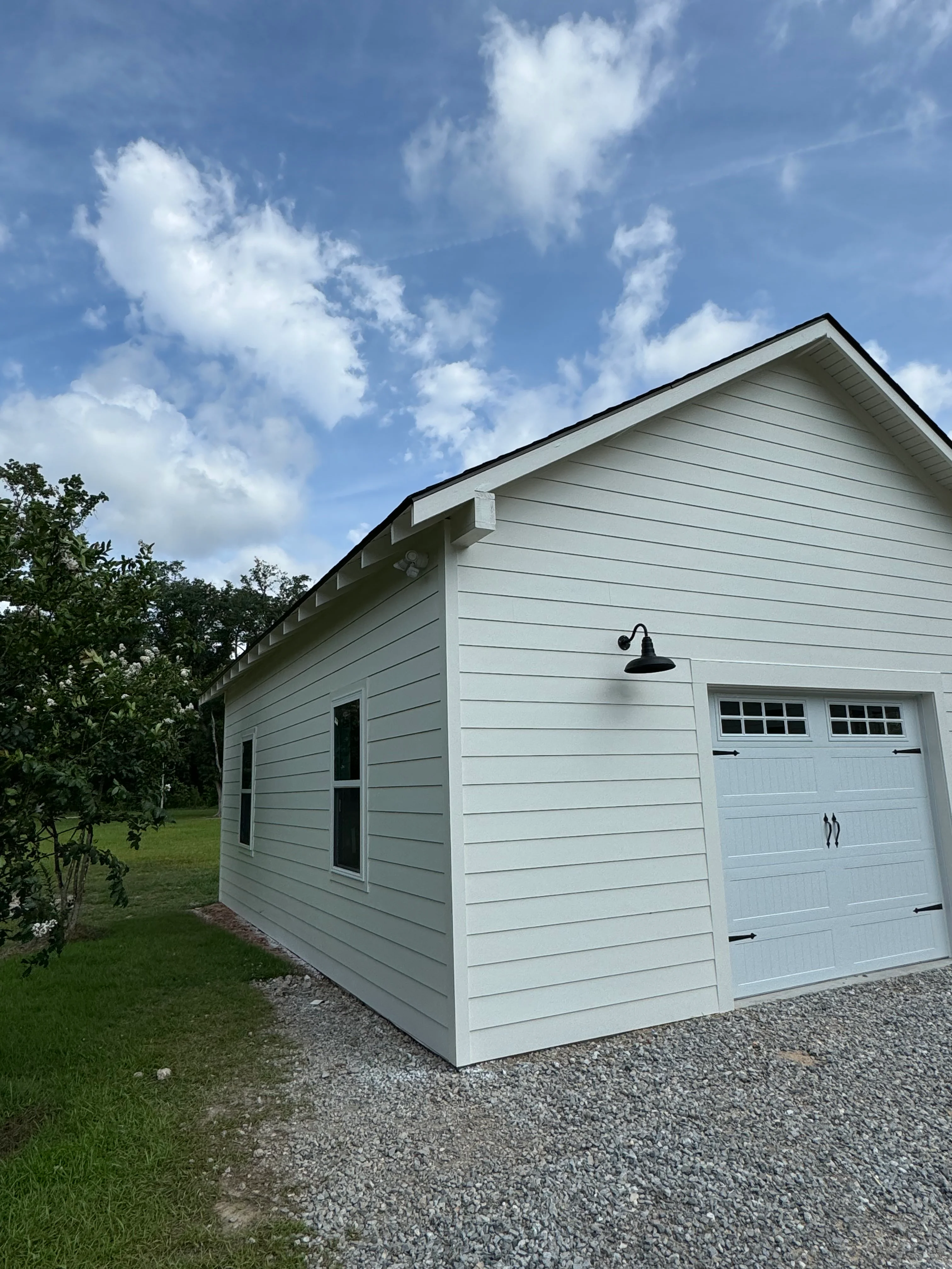 New light gray garage addition with gable roof and two-car garage door