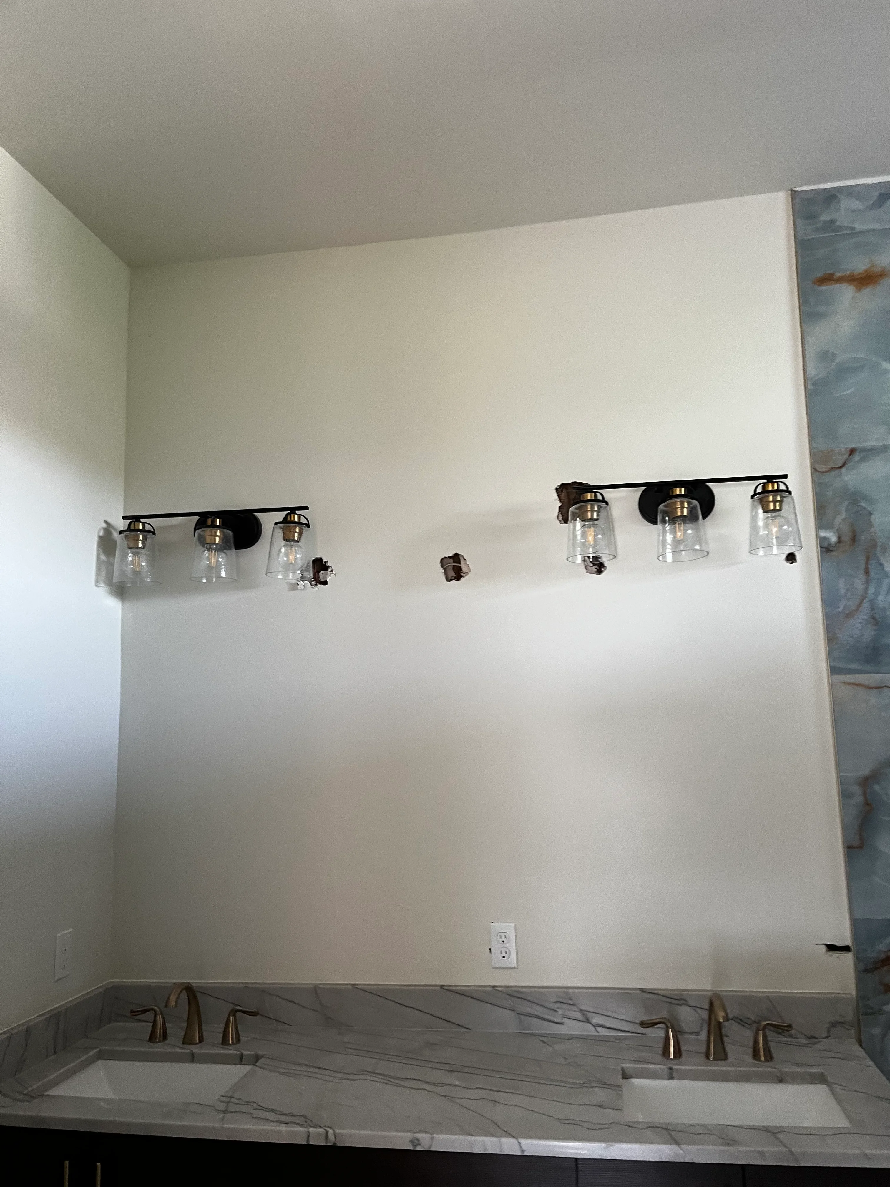 Modern bathroom vanity with marble countertop, dual faucets, and black vanity lights