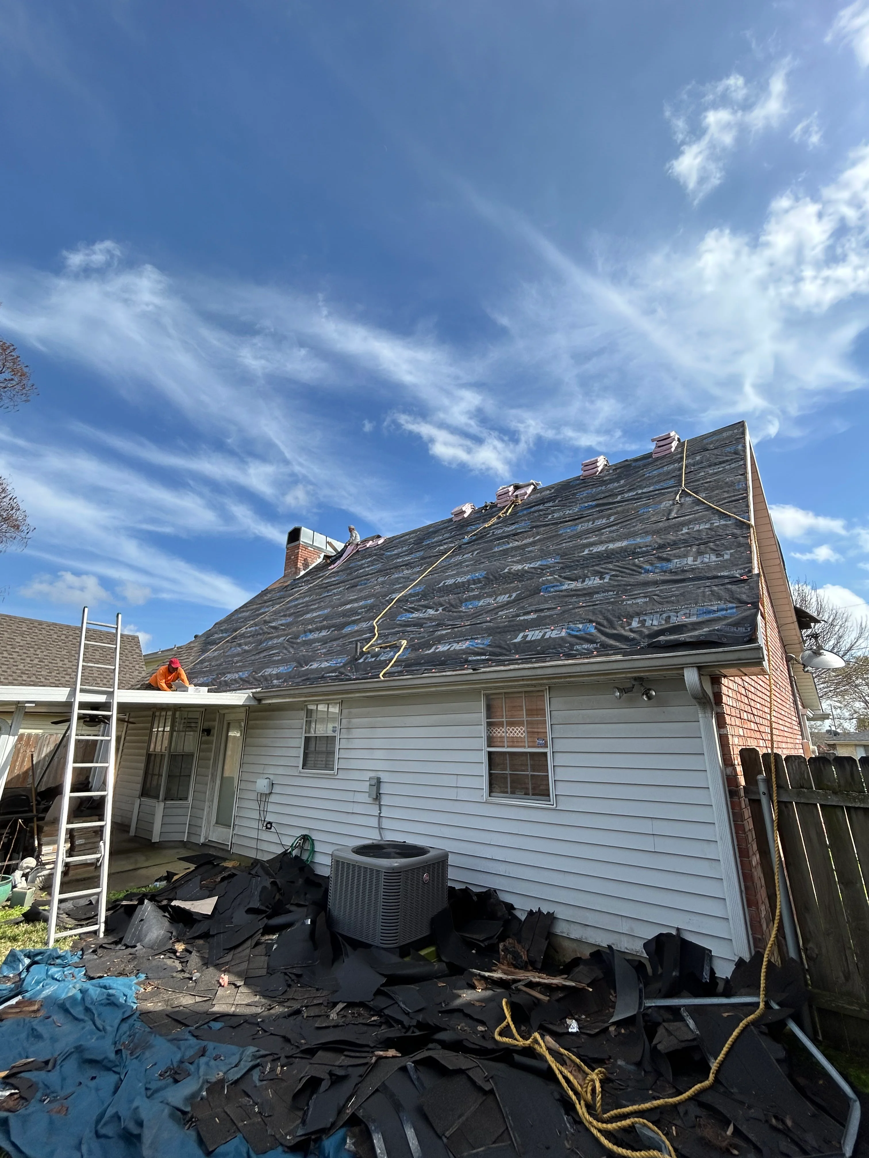Residential roof replacement in progress with old shingles removed and new materials staged
