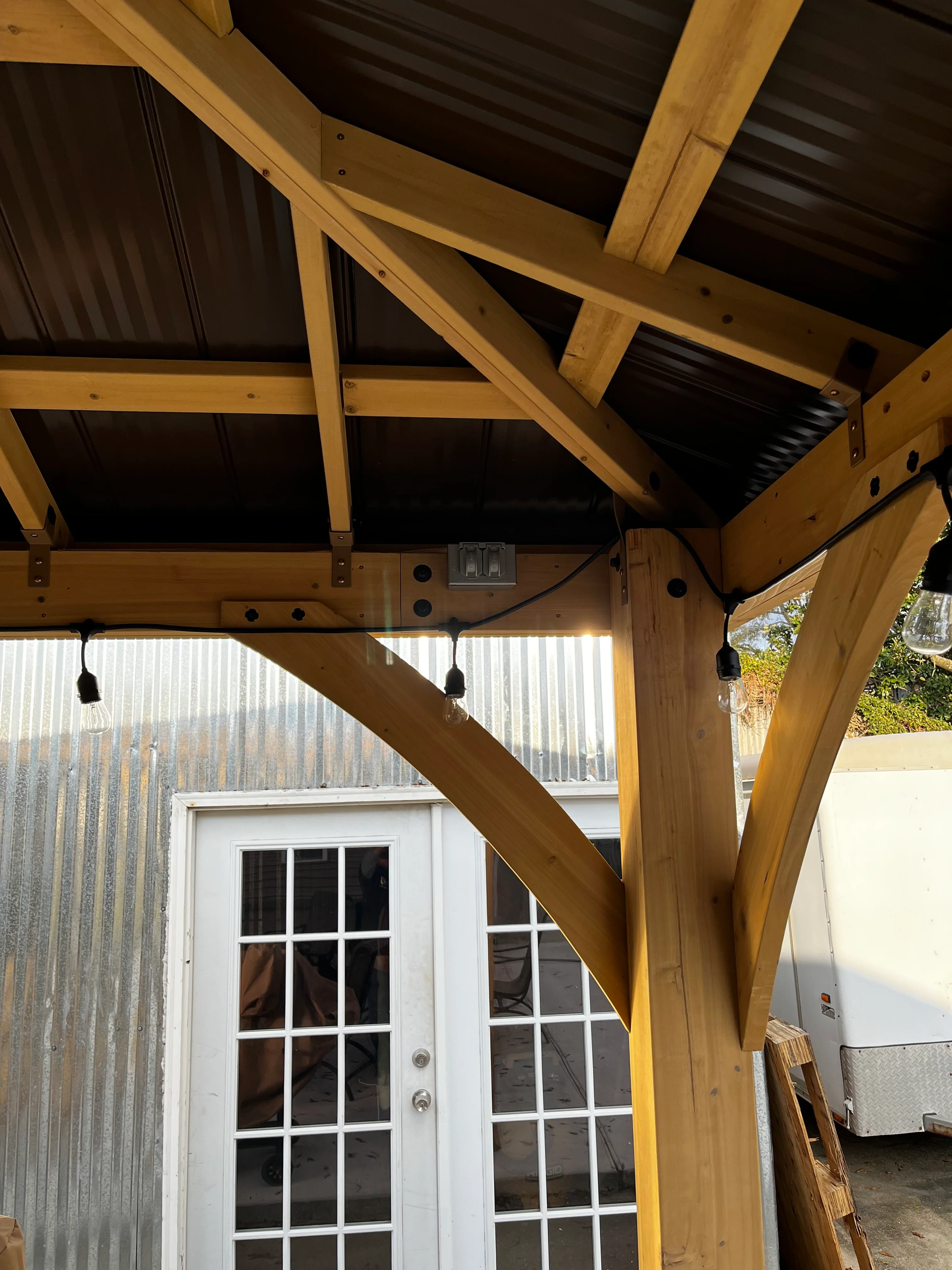 Timber pergola with corrugated metal roof and pendant lighting fixtures
