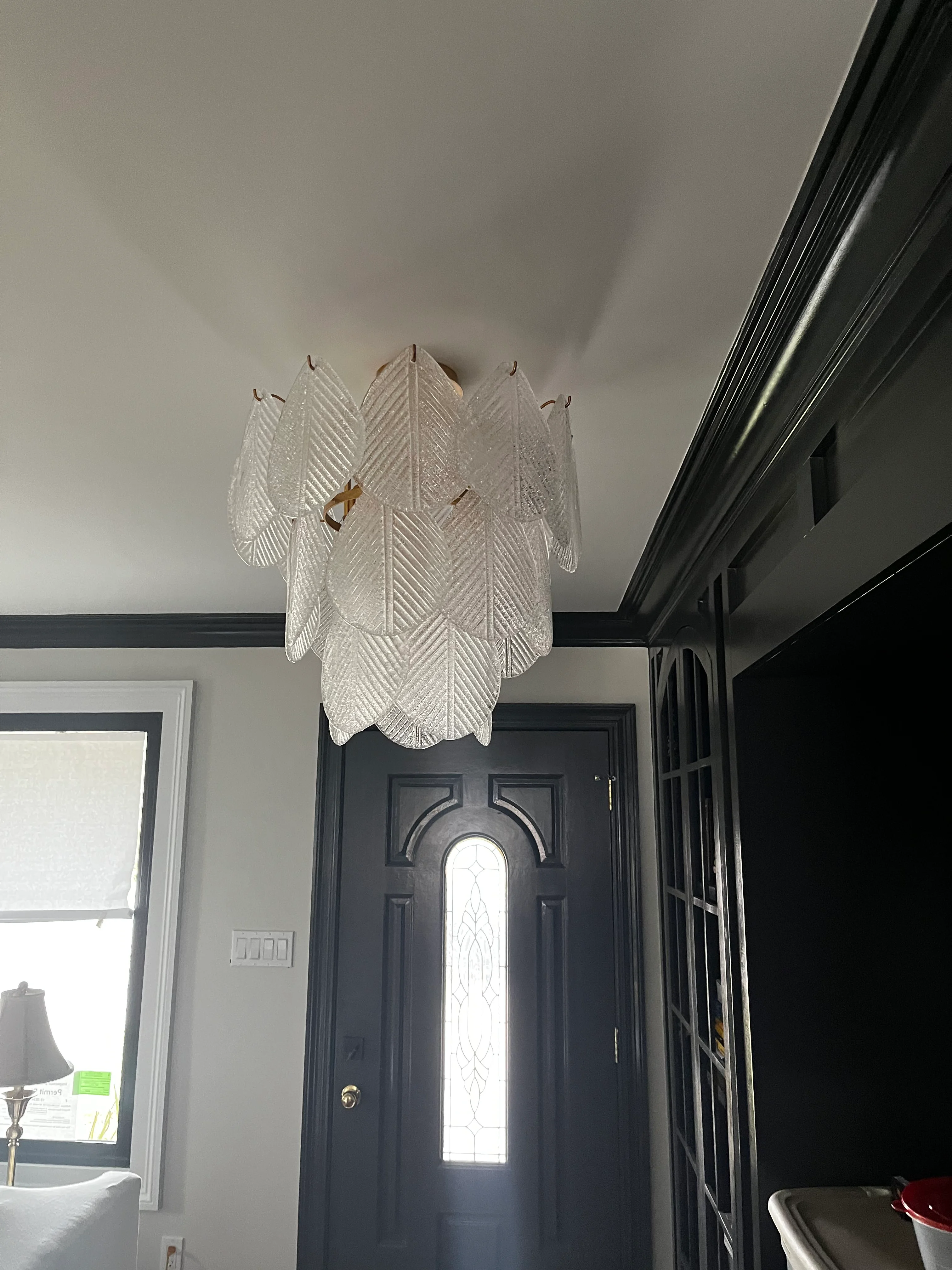 Frosted glass leaf pendant light installed above black entry door in foyer