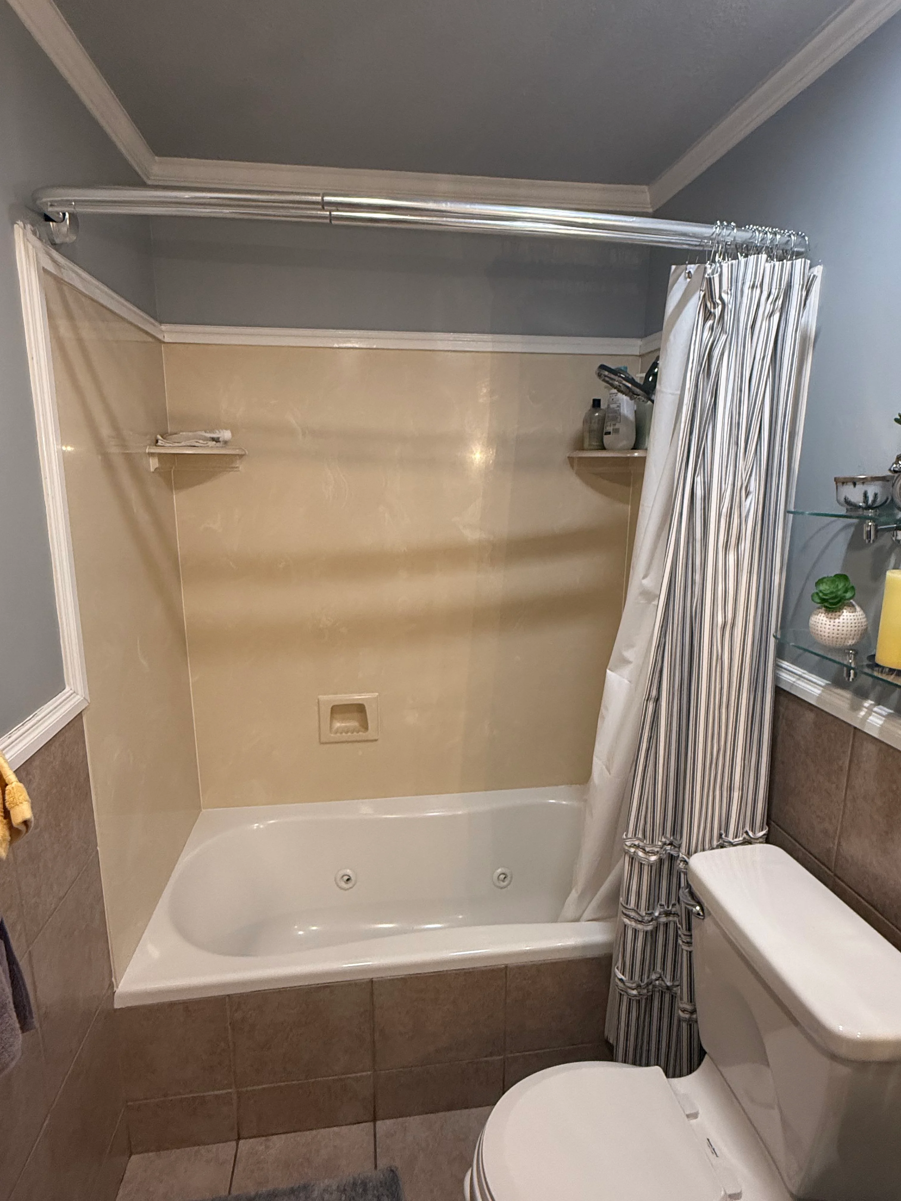 Newly renovated bathroom with white soaking tub, cream acrylic surround, and chrome fixtures