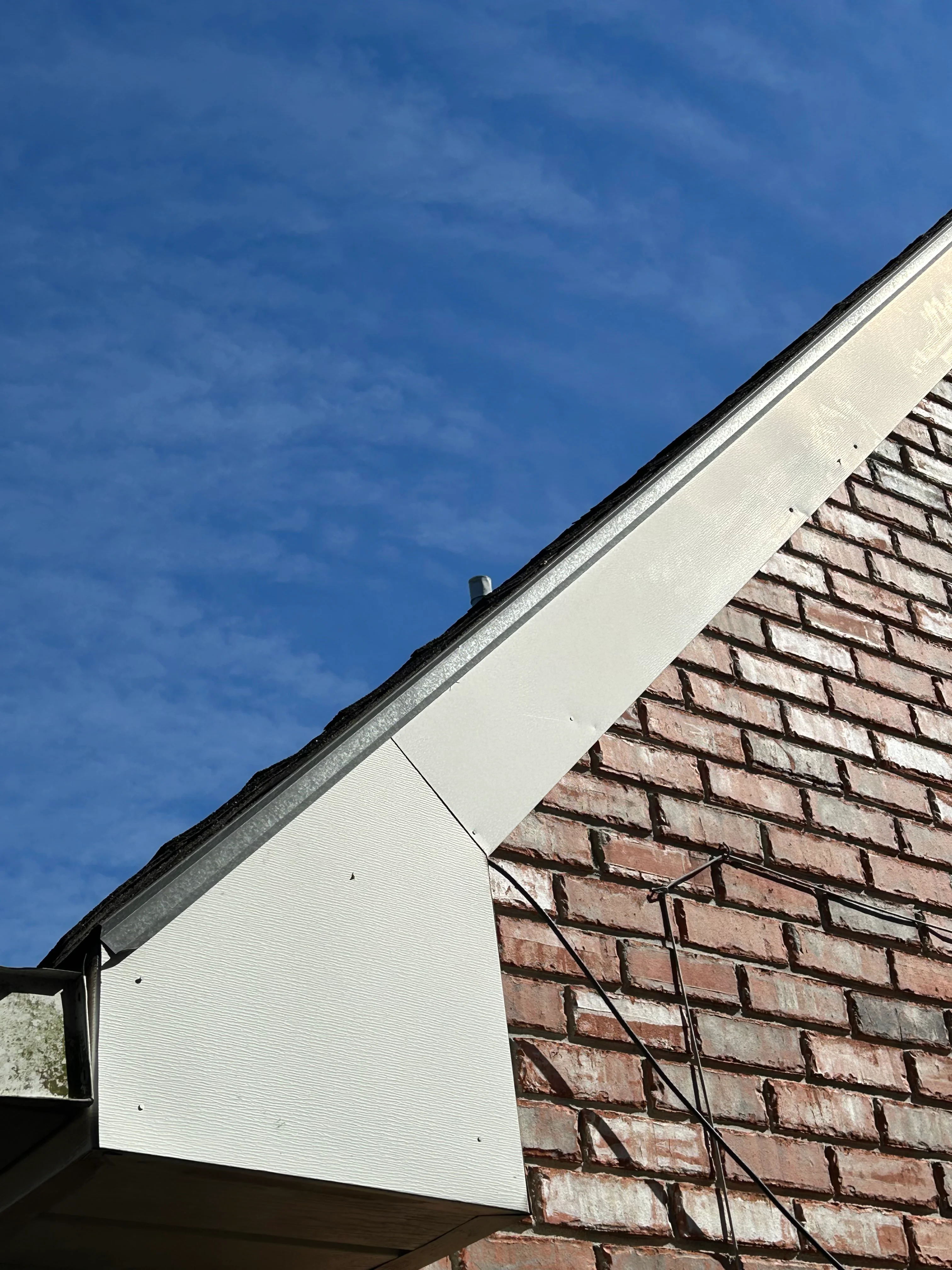New clay tile roof with white soffit and metal guttering against brick exterior
