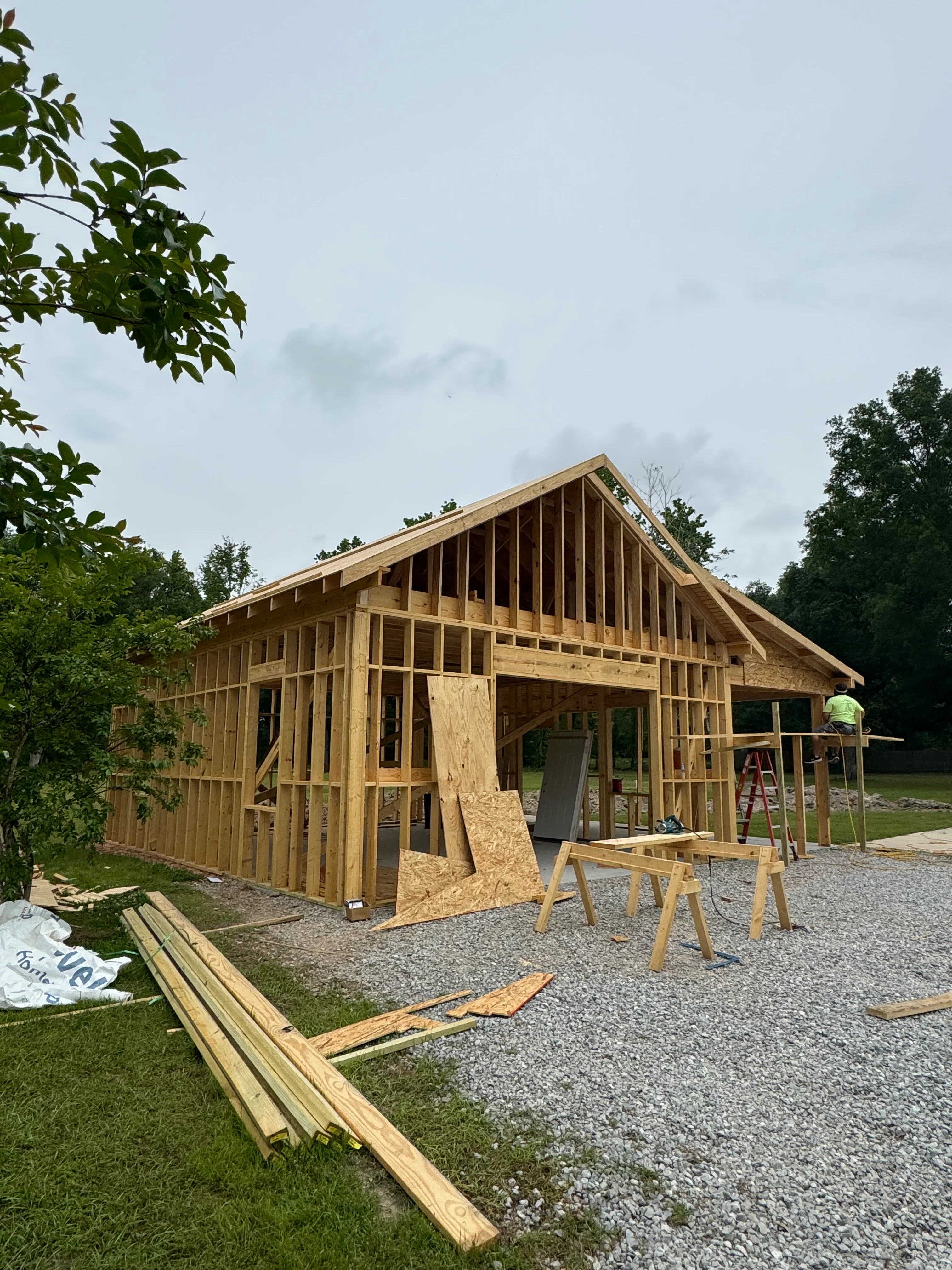 Wood-framed residential home under construction with exposed studs and roof trusses