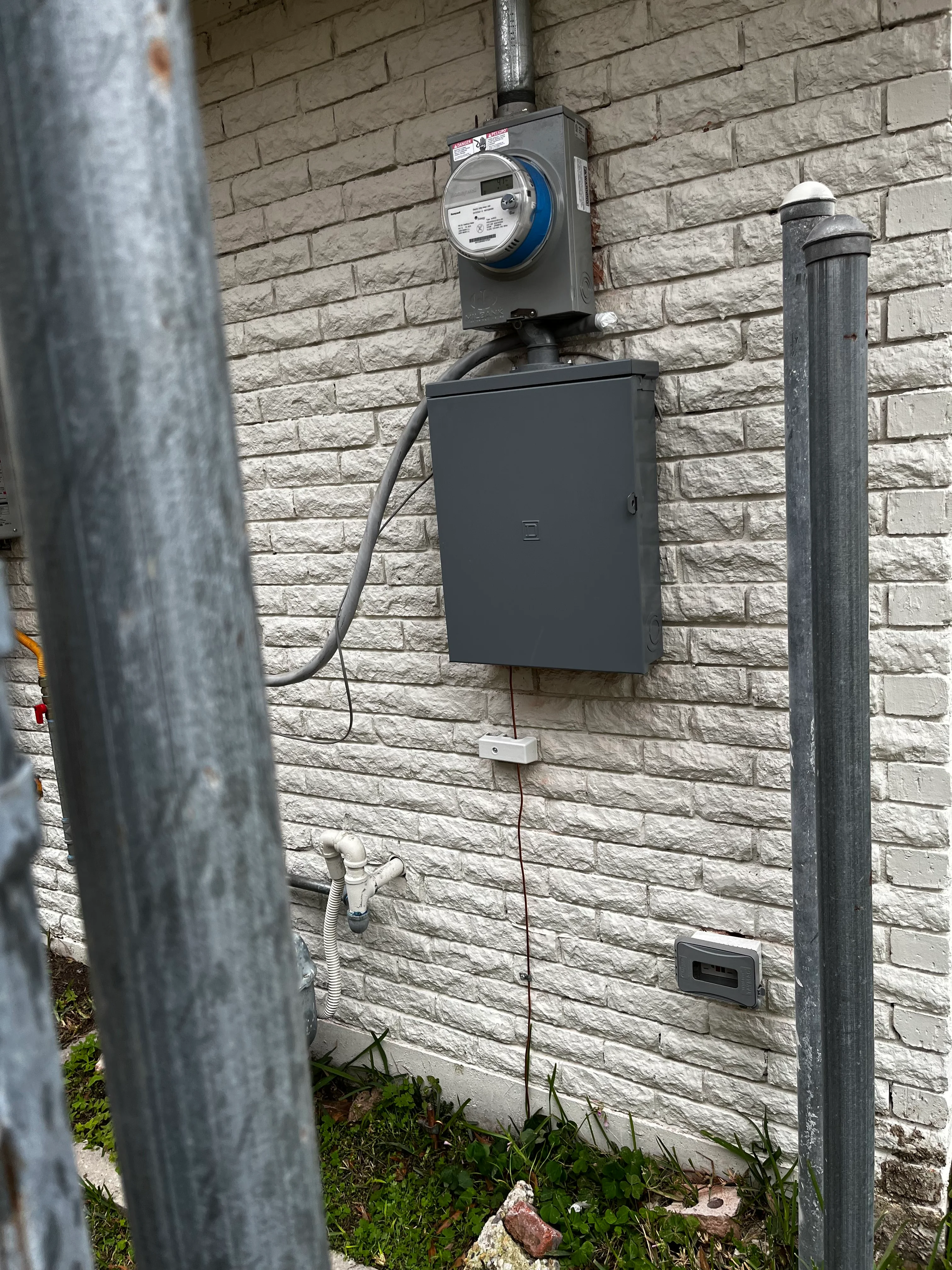 New electrical meter and disconnect box mounted on white brick wall