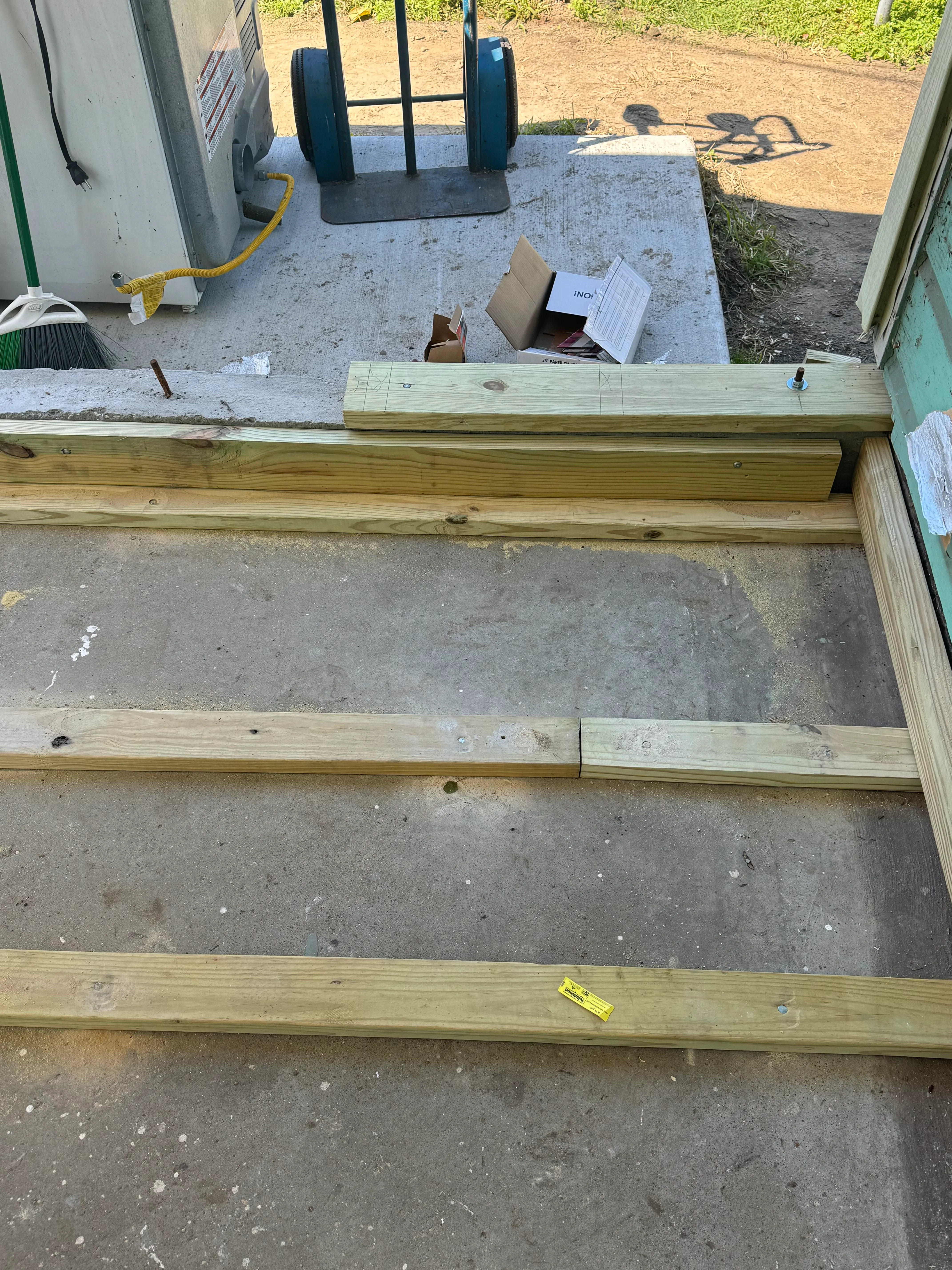Pressure-treated lumber framing on concrete foundation during construction phase