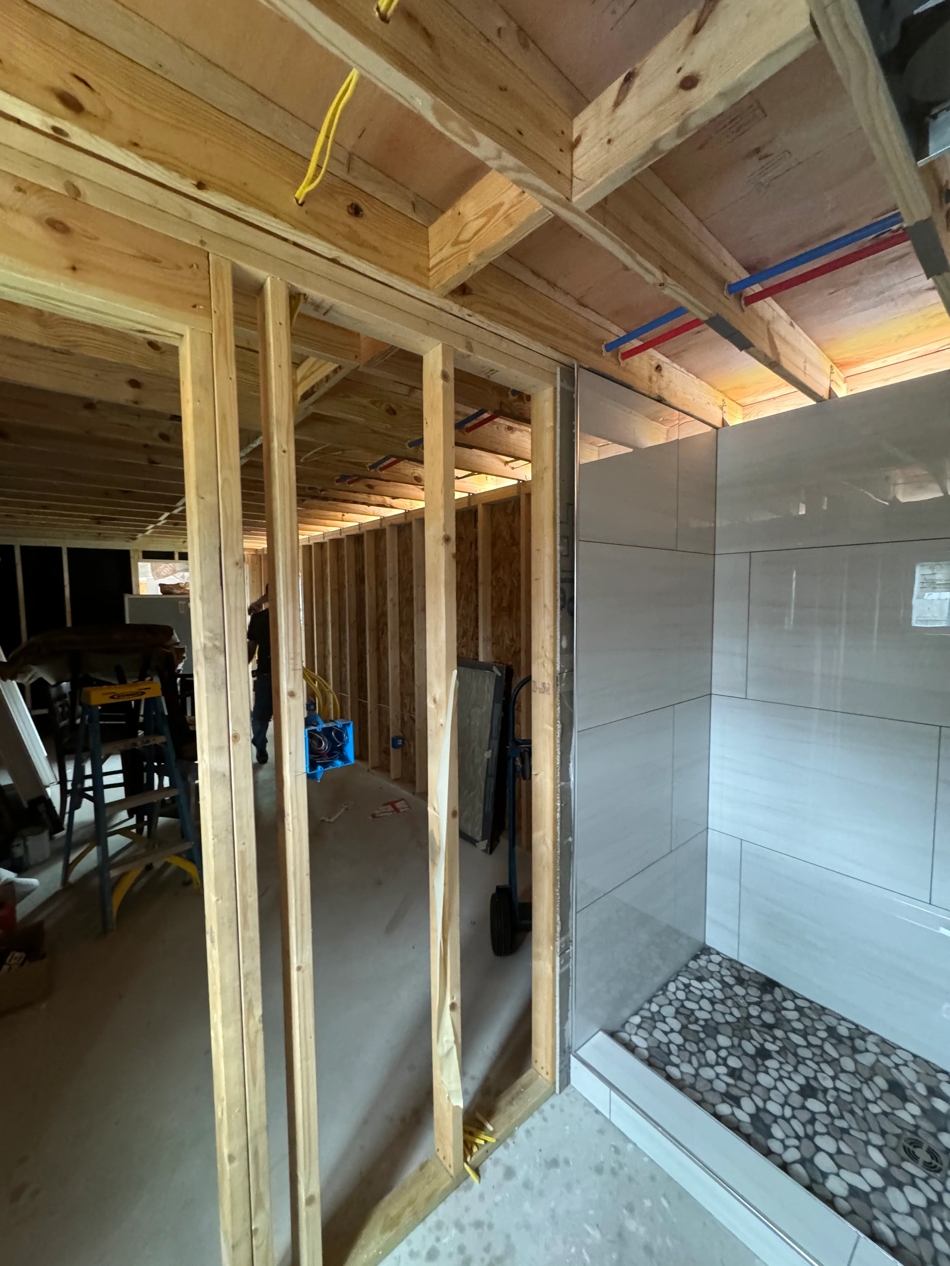 Bathroom under construction with wooden framing, tiled shower enclosure, and pebble floor