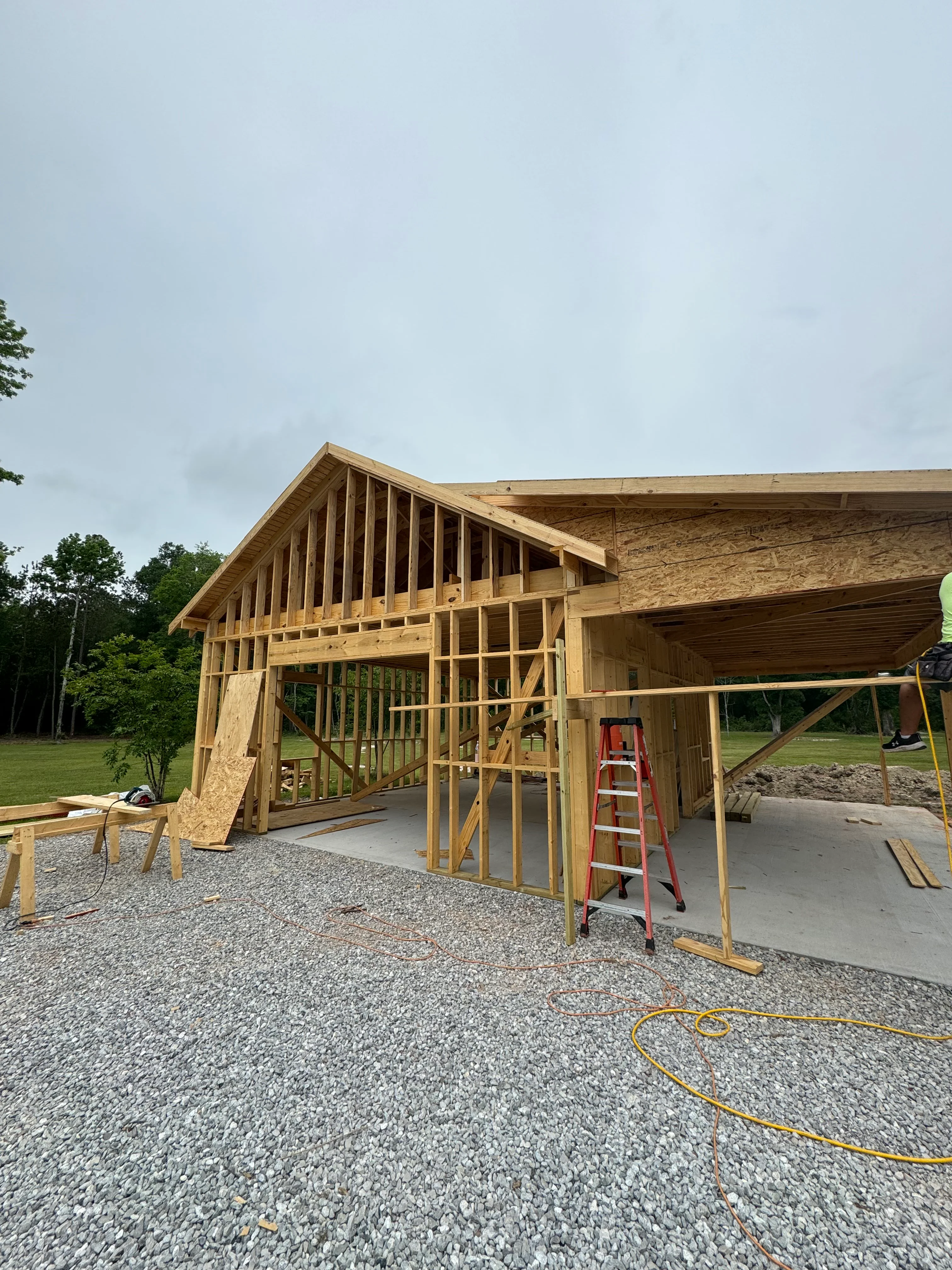 Wood-framed residential home under construction with exposed framing and concrete foundation