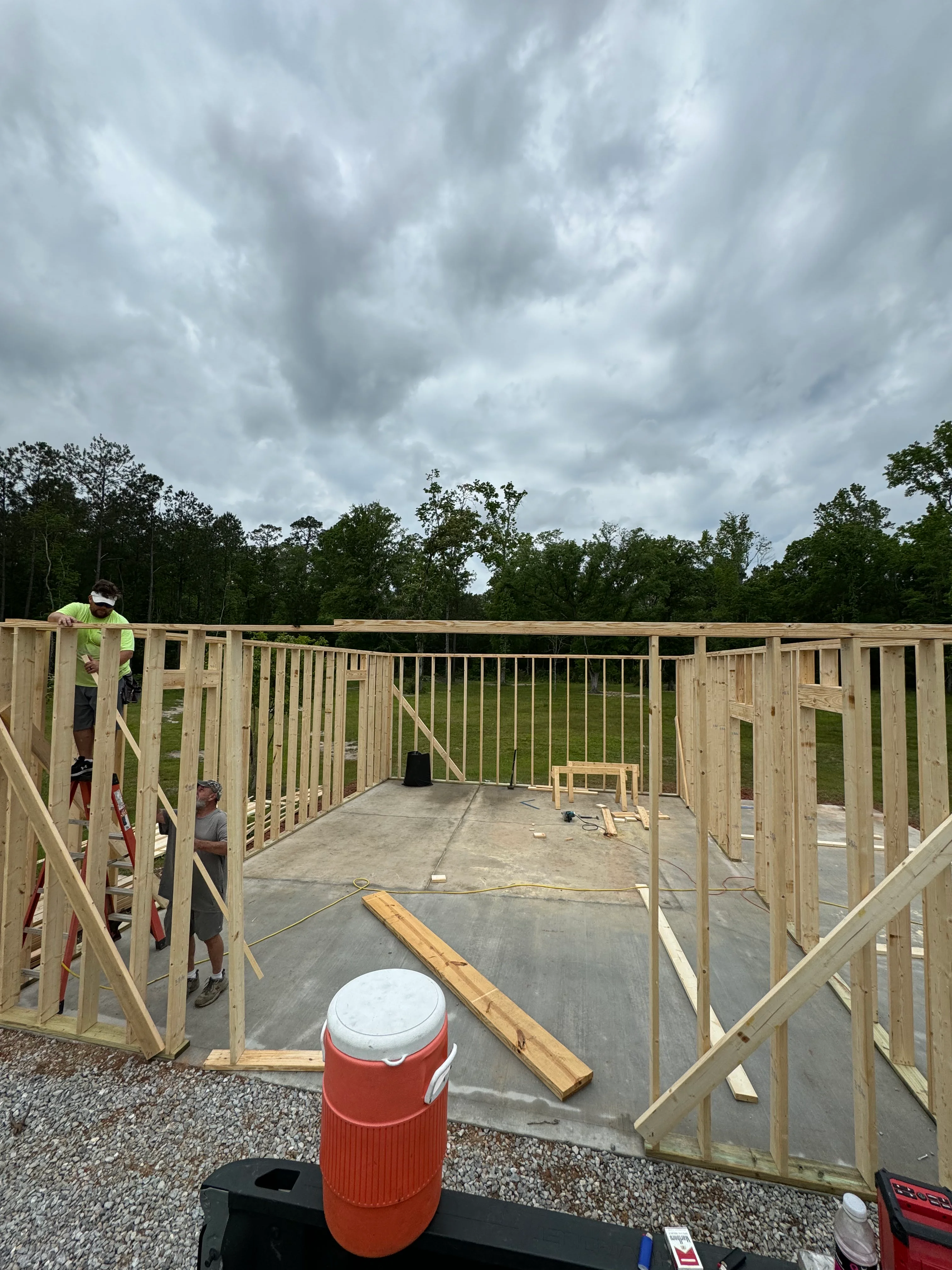 Deck framing construction with wooden posts, beams, and railings on concrete foundation