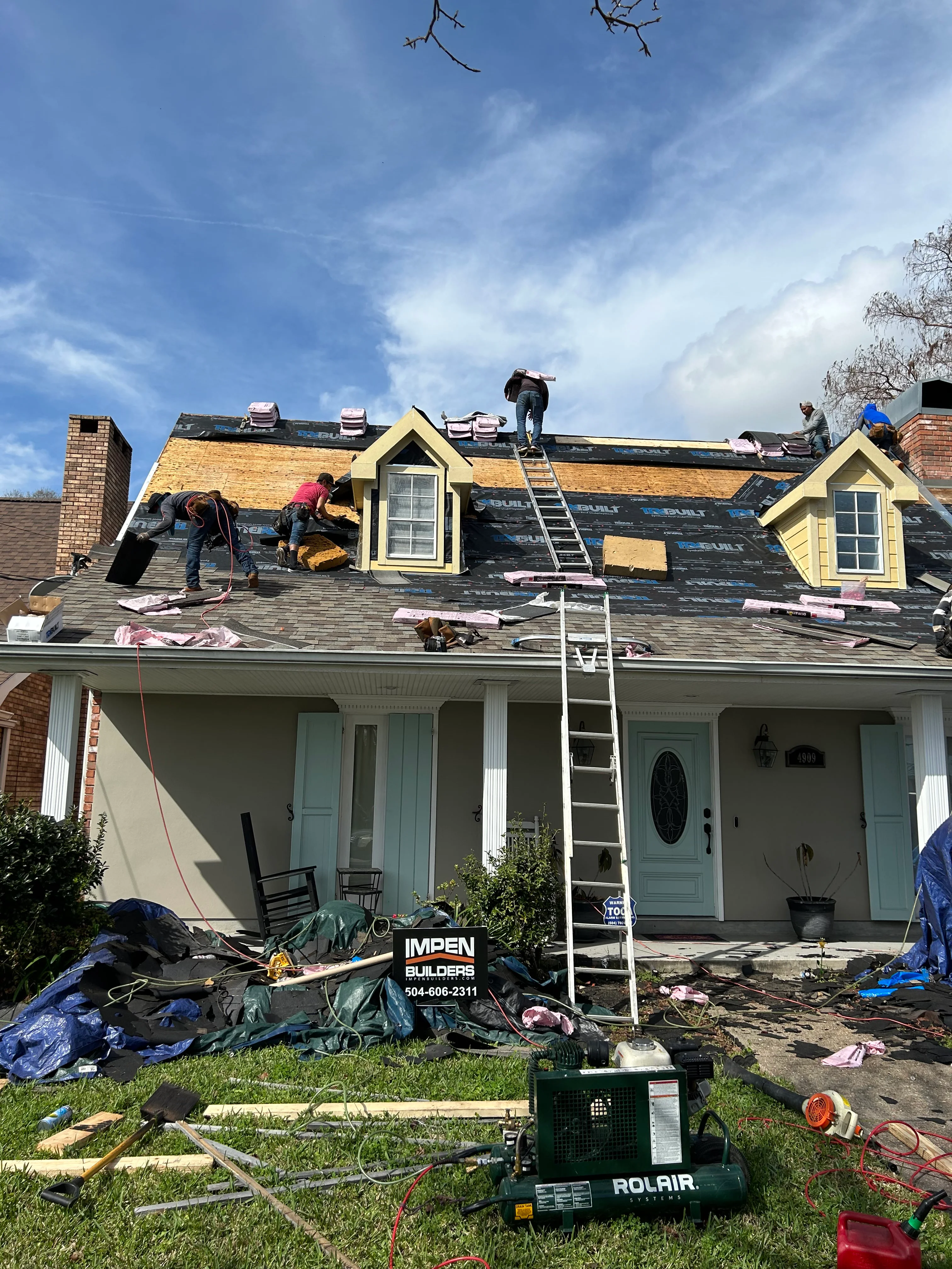 Roofing crew installing new shingles on residential home with dormers in New Orleans
