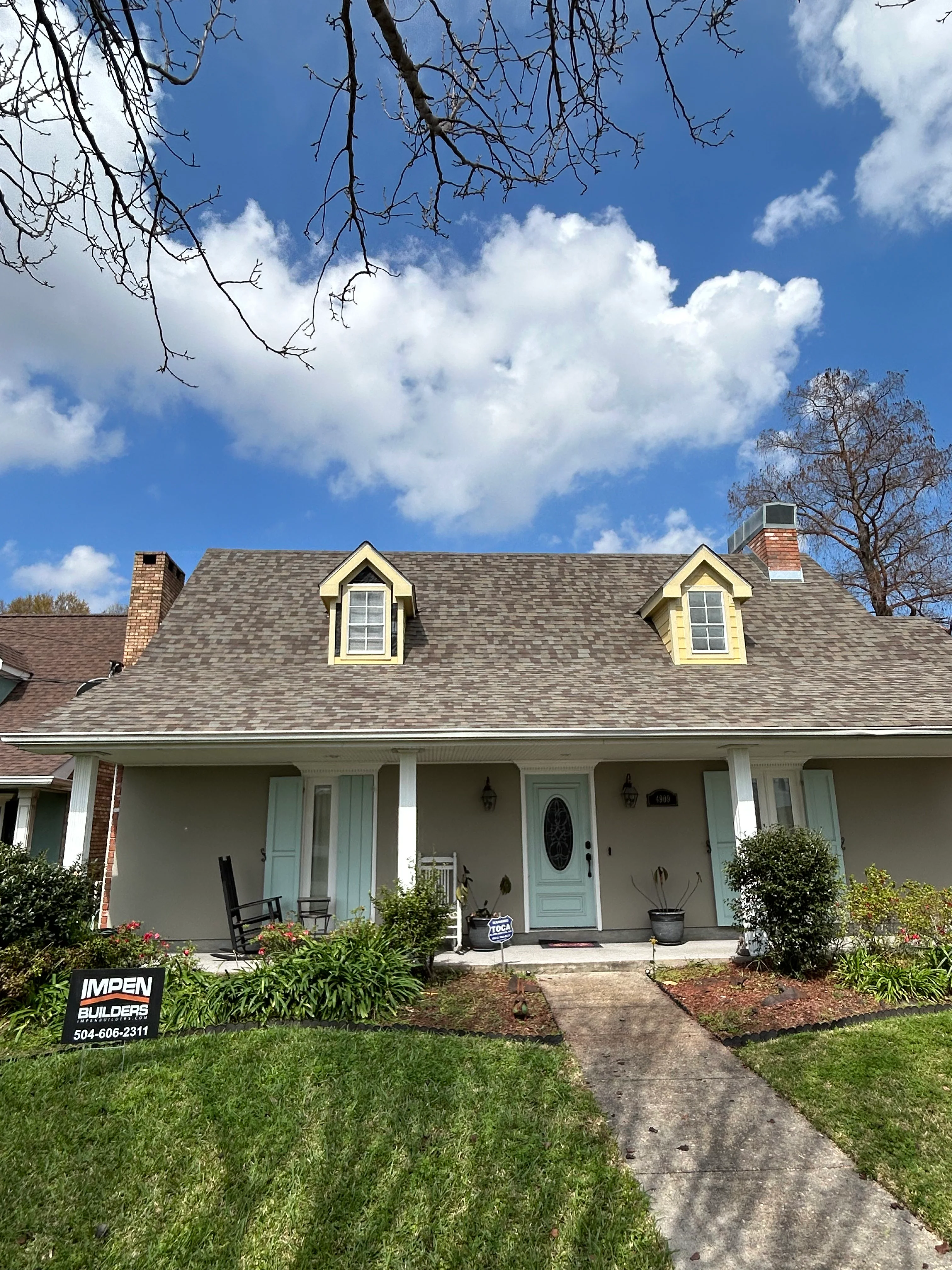 Cream brick home with new gray shingle roof, white porch columns, and updated entry door