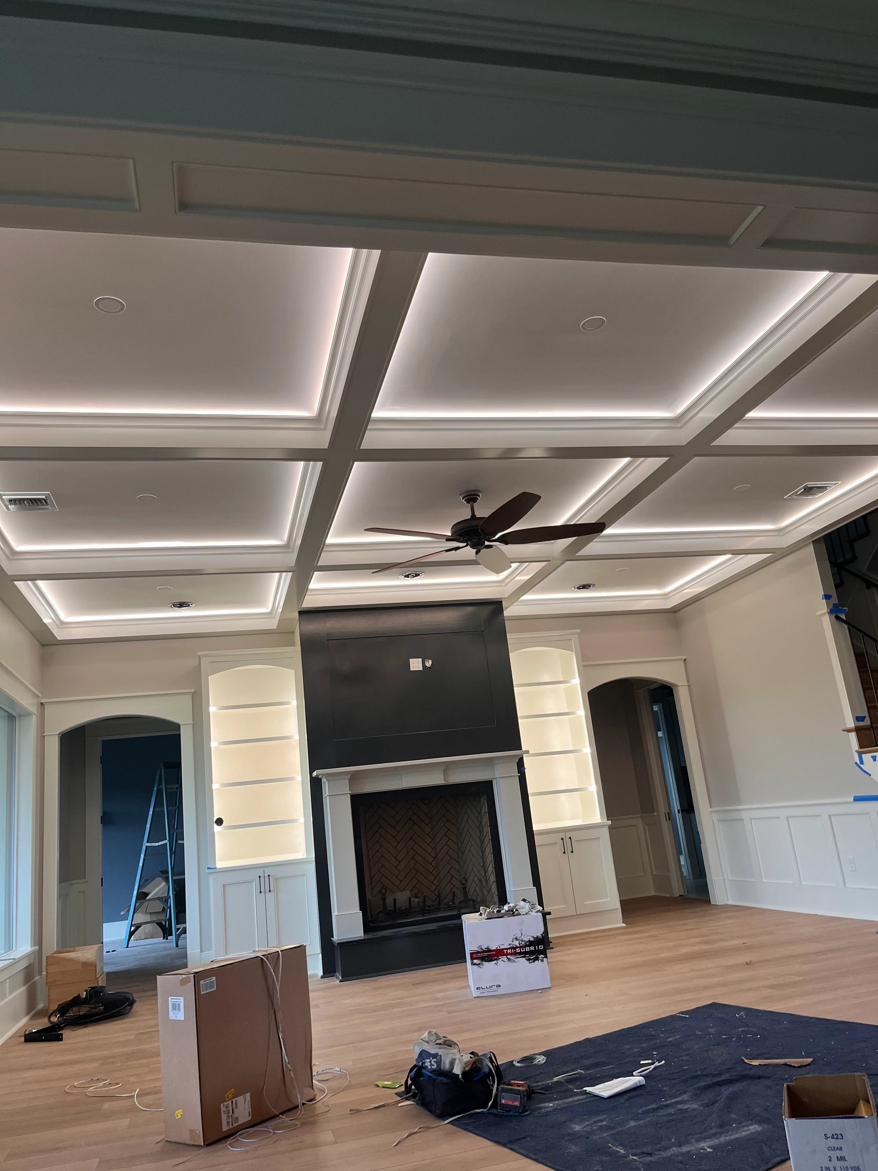 Modern coffered ceiling with LED lighting and fireplace surround with white cabinetry