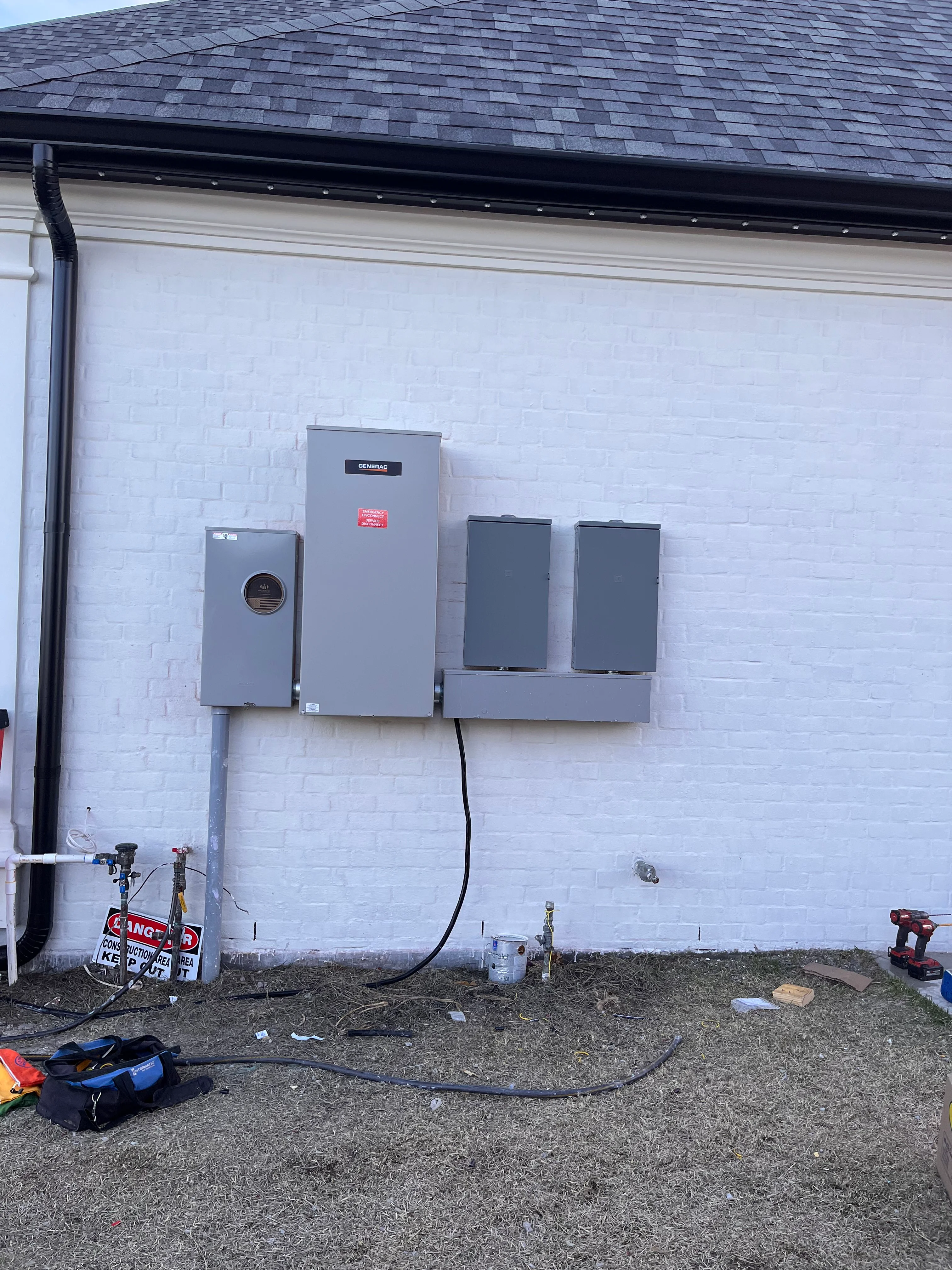 Generac generator and battery backup system installed on white brick exterior wall