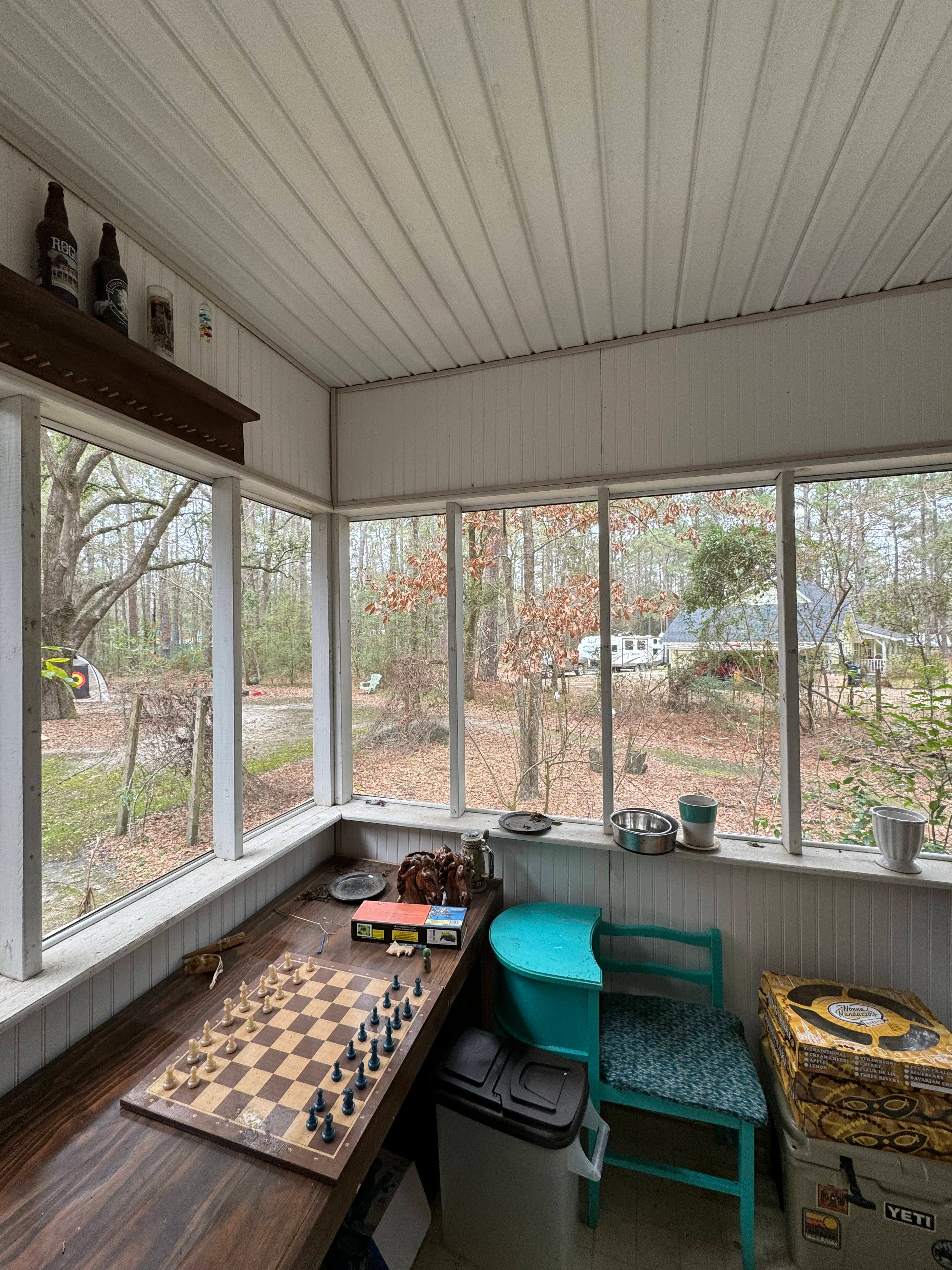 Interior of screened porch with metal roof, large windows, and wood flooring