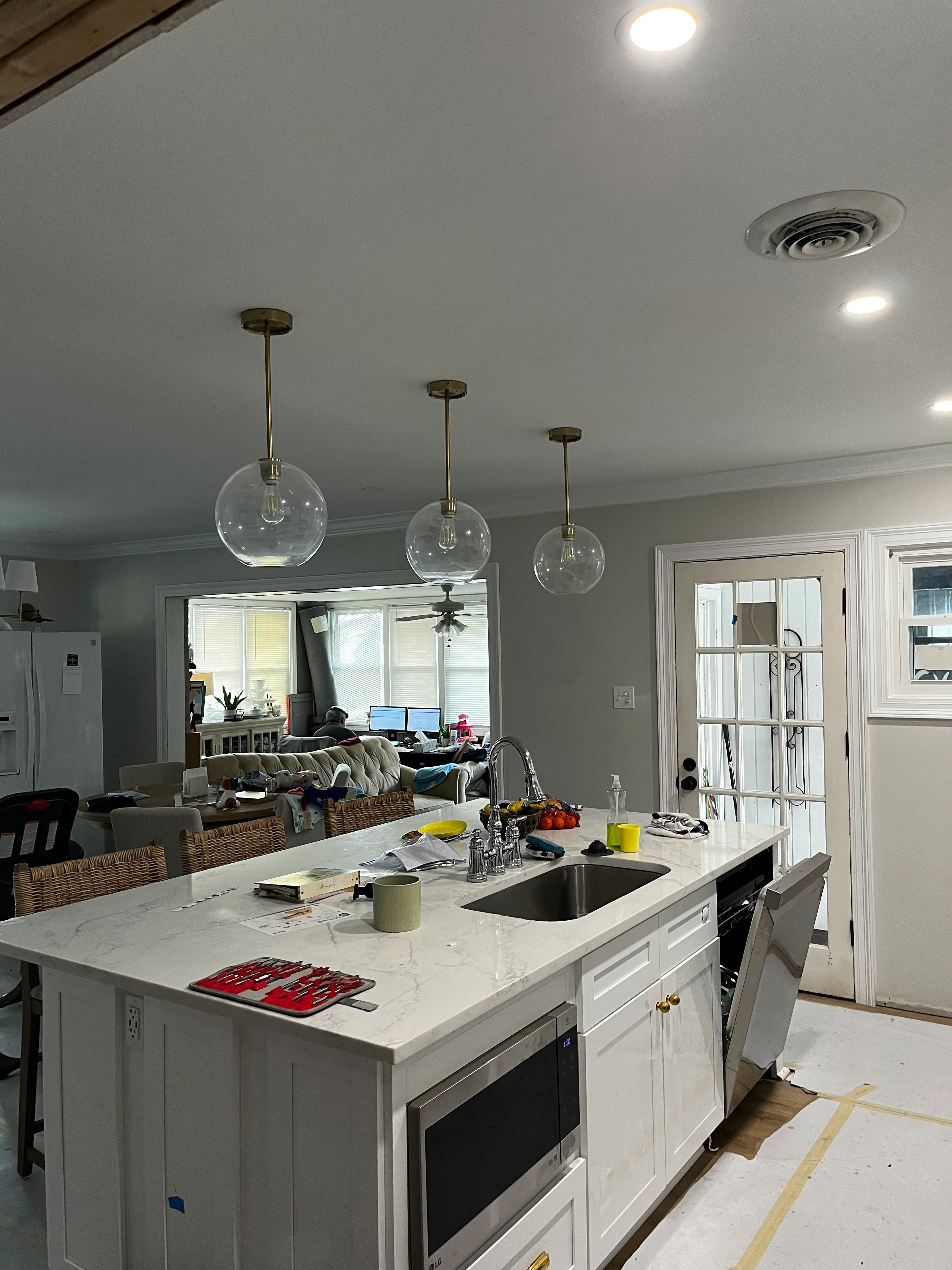 Modern kitchen with white island, marble counters, and three glass pendant lights