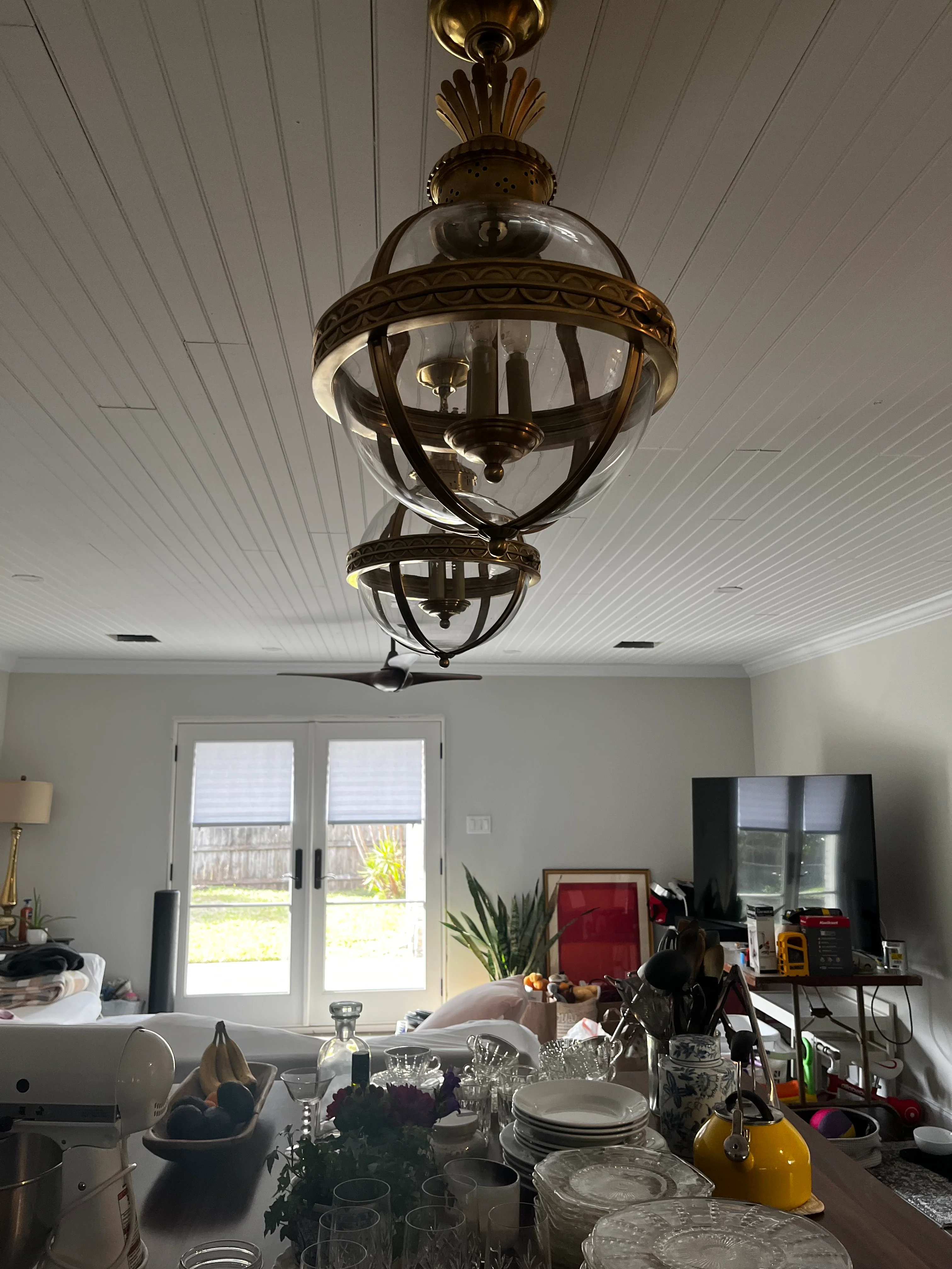 Ornate brass pendant light hanging from white shiplap ceiling in modern kitchen