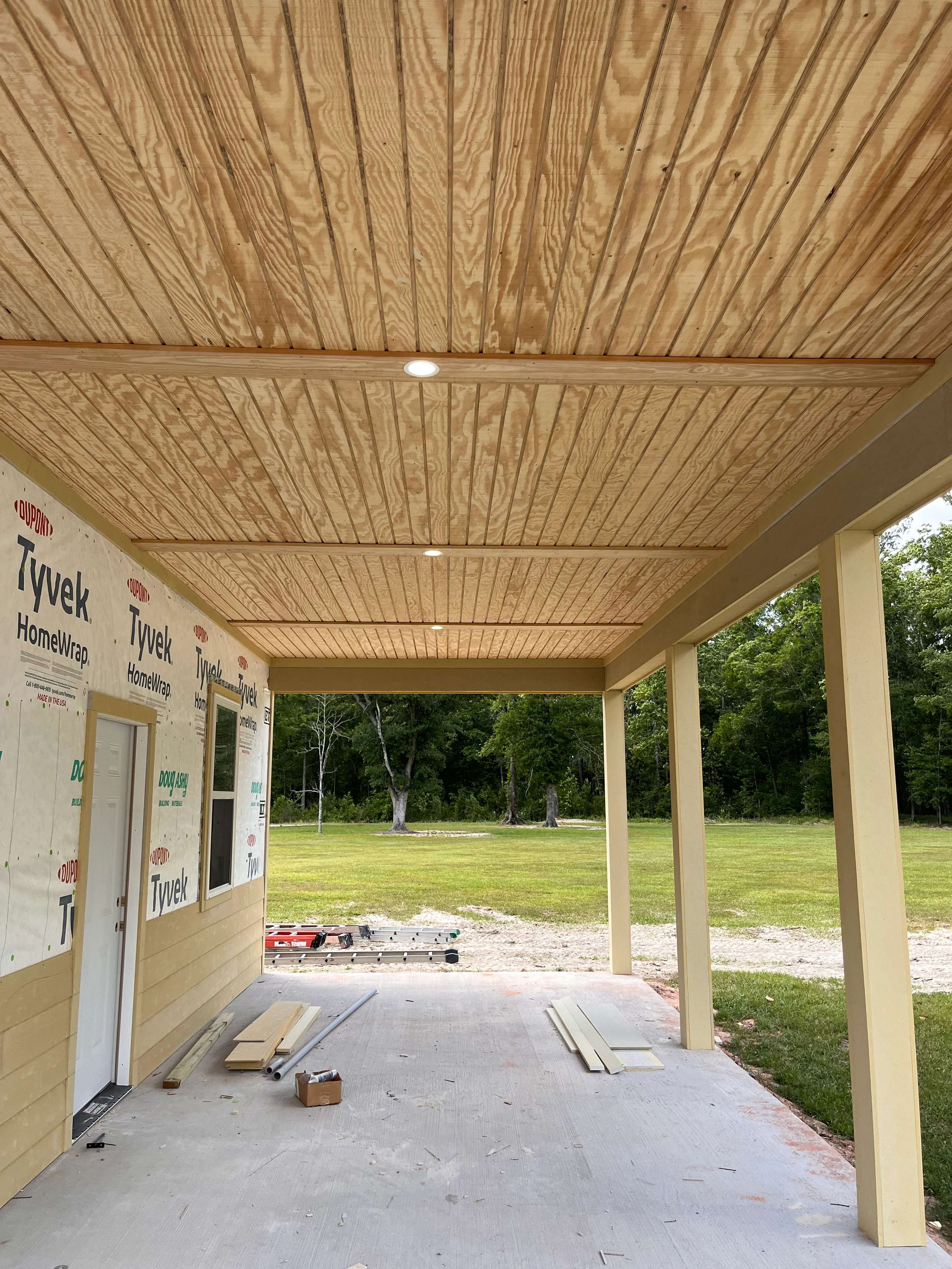 Wood soffit ceiling patio with support columns and concrete foundation during construction